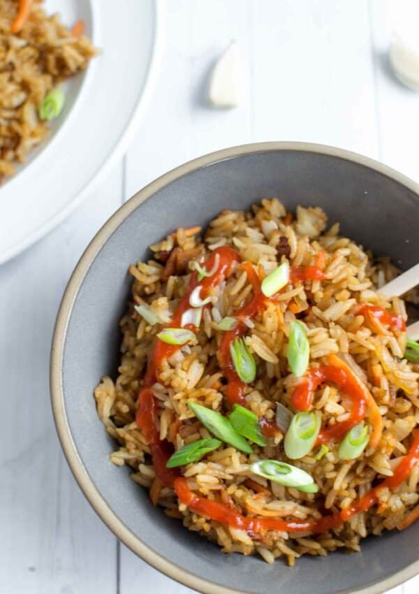 fried rice in bowl with sriracha and scallions
