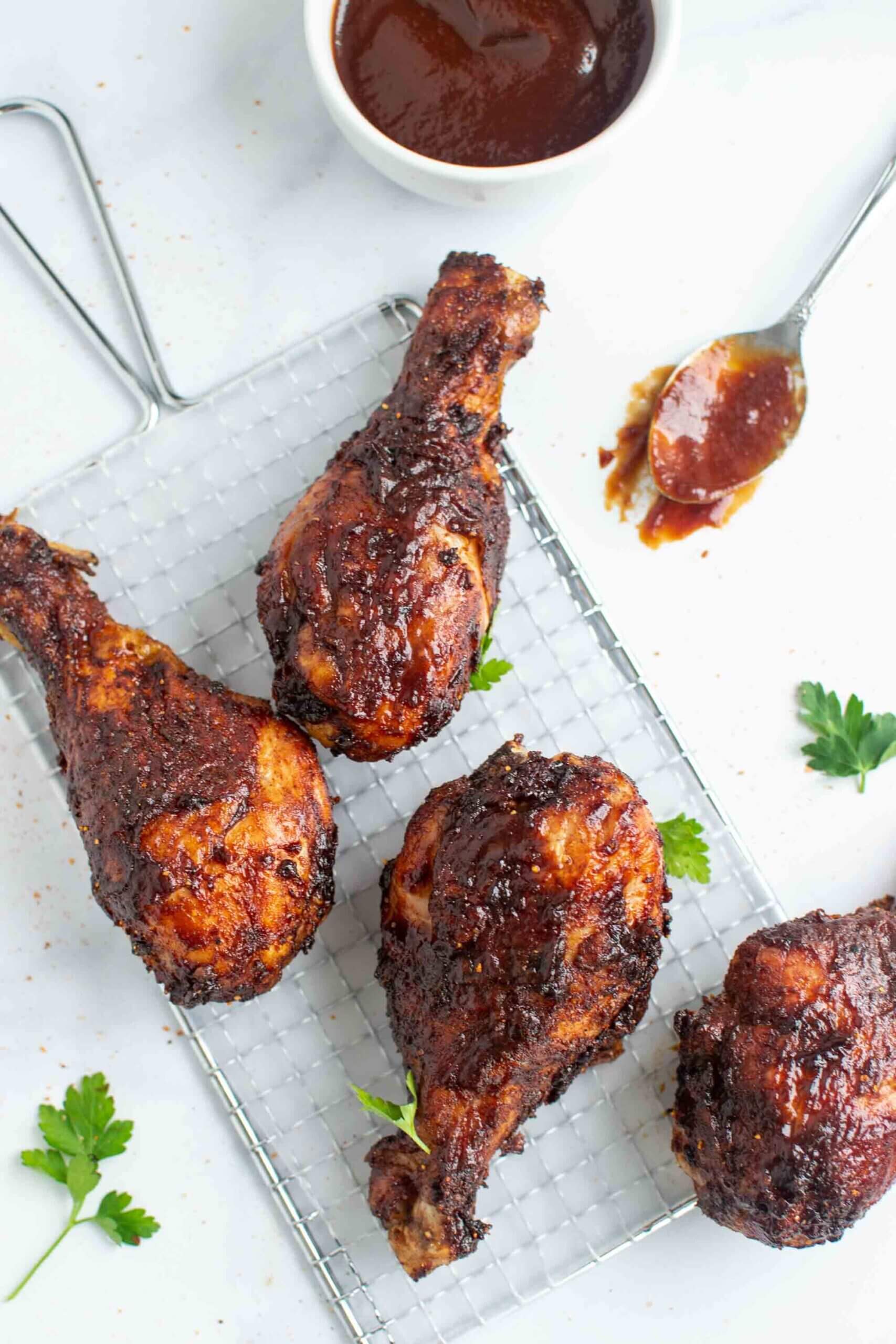 Four air fryer chicken legs with BBQ sauce, garnished with cilantro