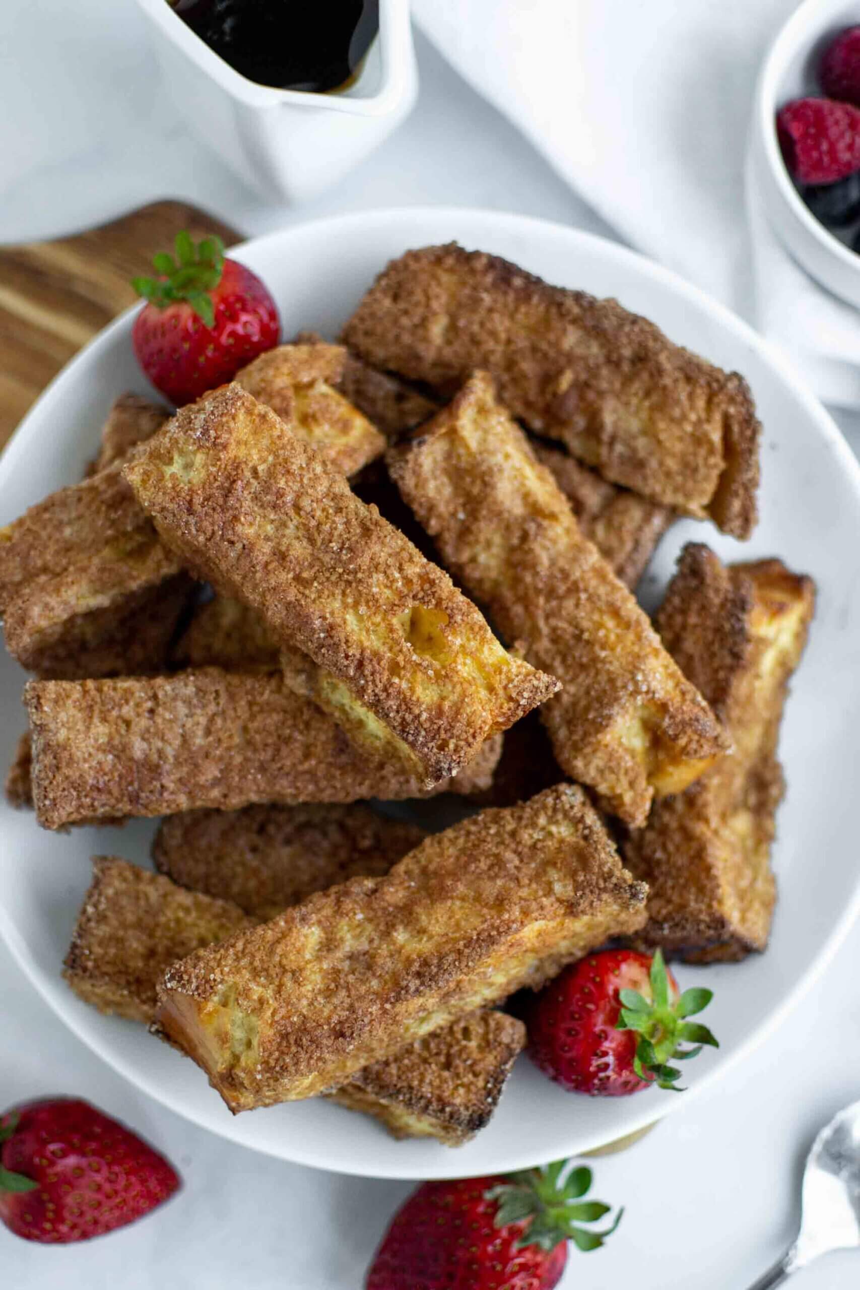 Air Fryer French Toast Sticks on a plate with strawberries.