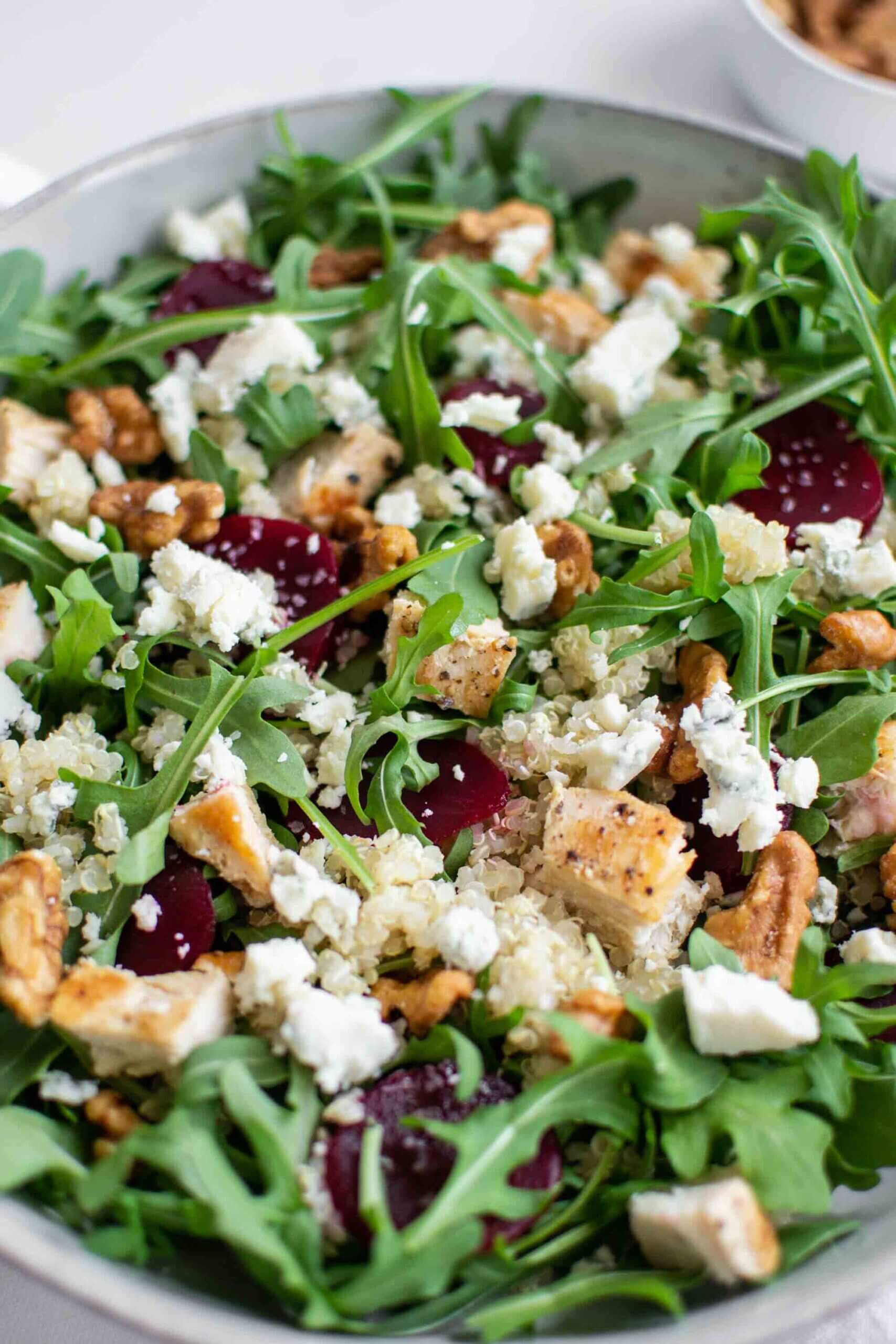 Quinoa and arugula salad in a bowl with beets, chicken and gorgonzola cheese