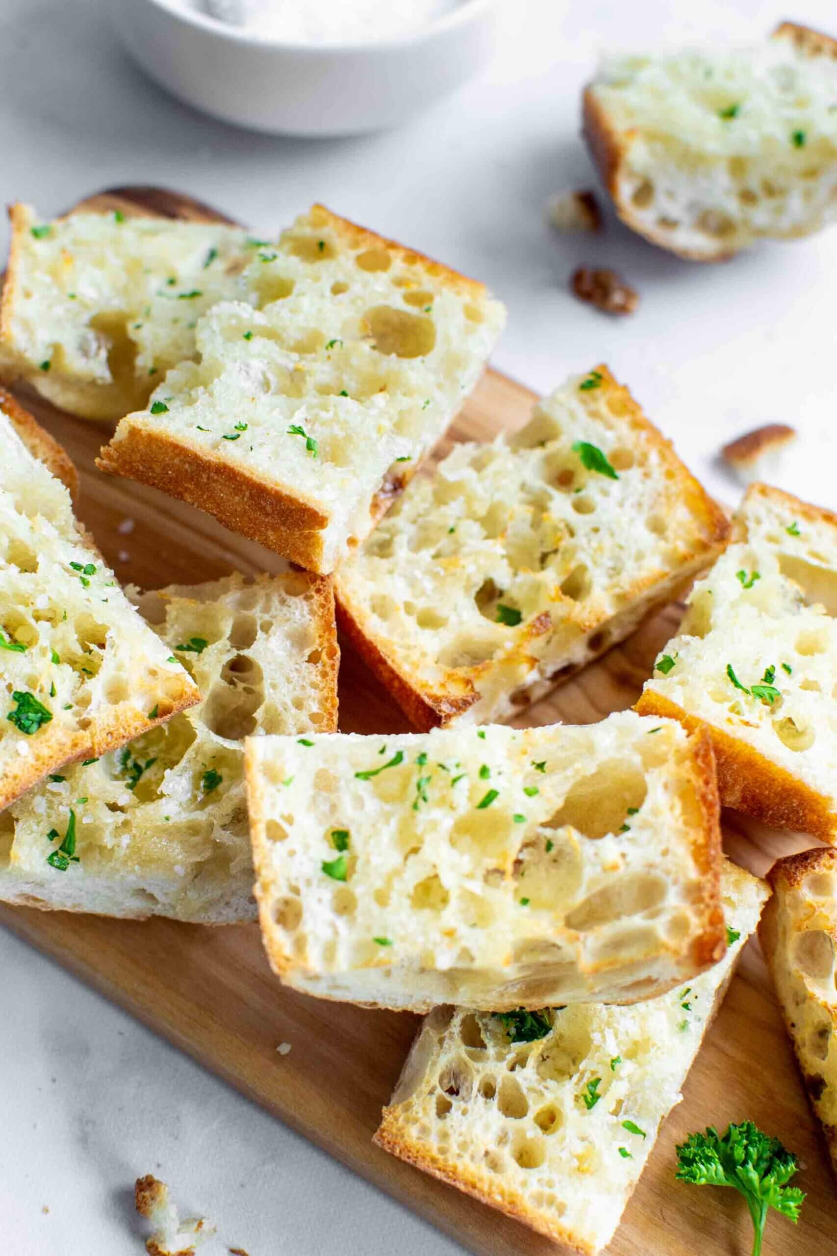 Pieces of air fryer garlic bread on a cutting board with parsley.