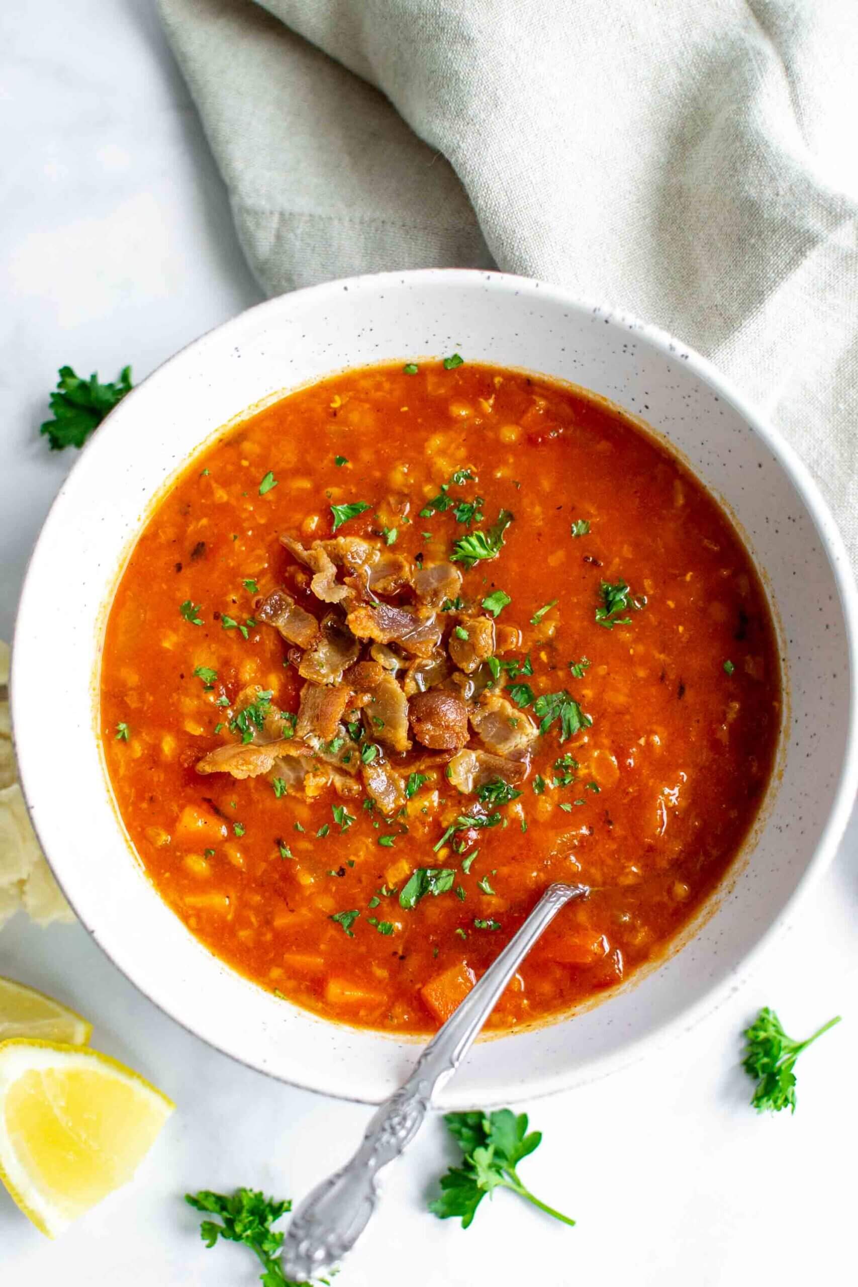 One bowl of Instant Pot Red Lentil Soup with parsley garnished with bacon
