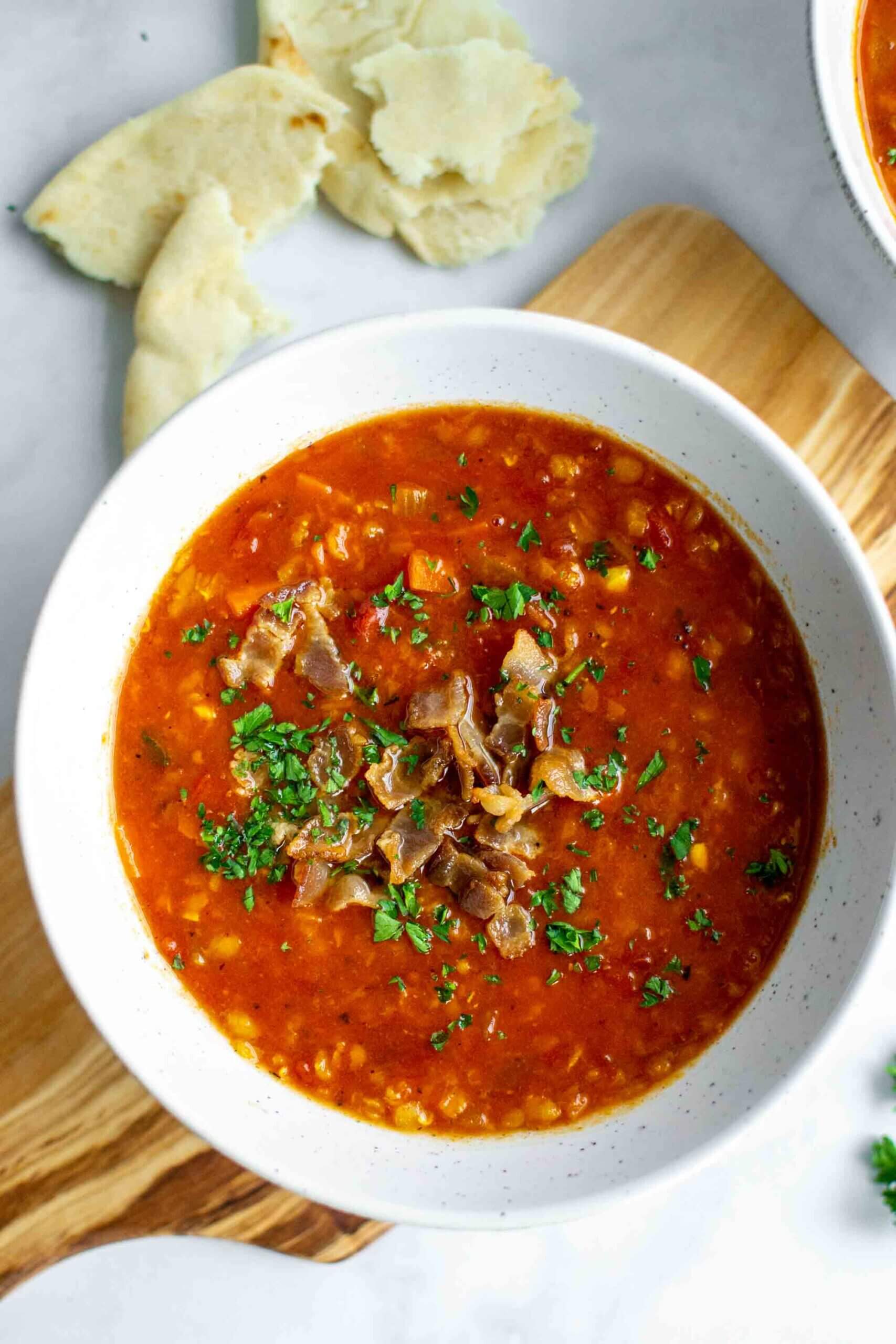 Two bowls of Instant Pot Red Lentil Soup with parsley garnished with bacon