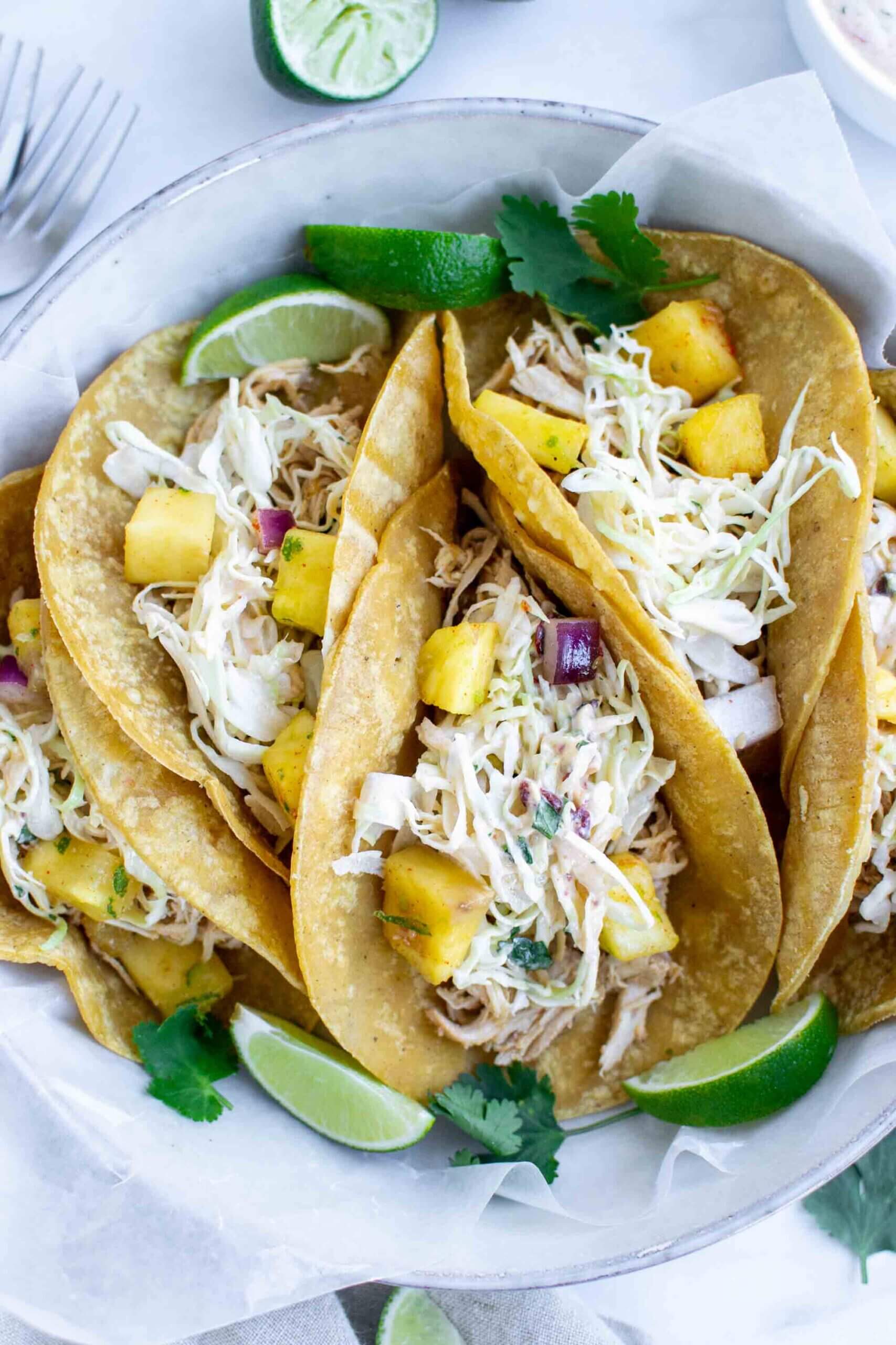 Four Crockpot Hawaiian Chicken Tacos on a plate with lime