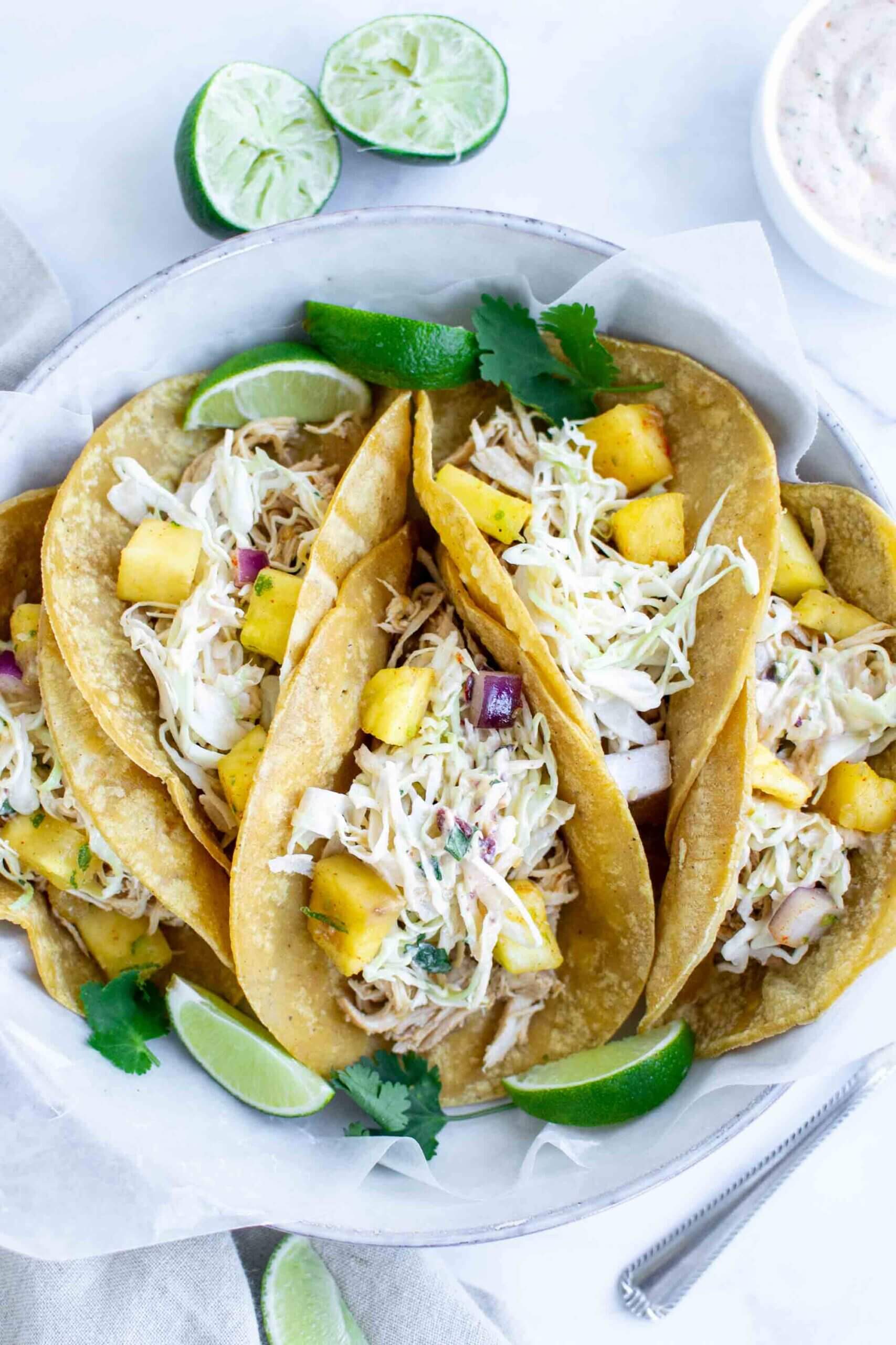 Four Crockpot Hawaiian Chicken Tacos on a plate with lime
