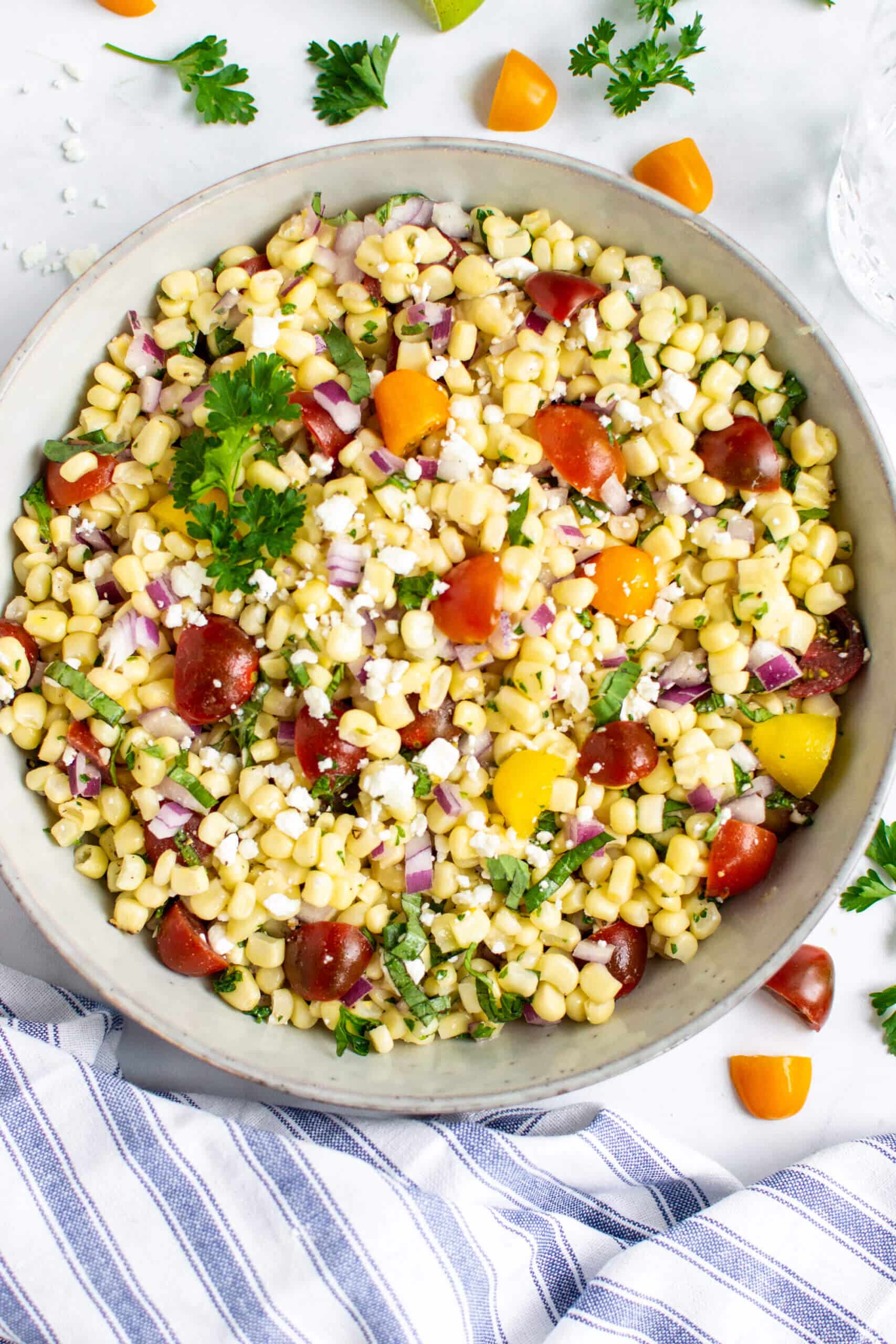 Simple sweet corn salad in a bowl with cherry tomatoes and red onion.