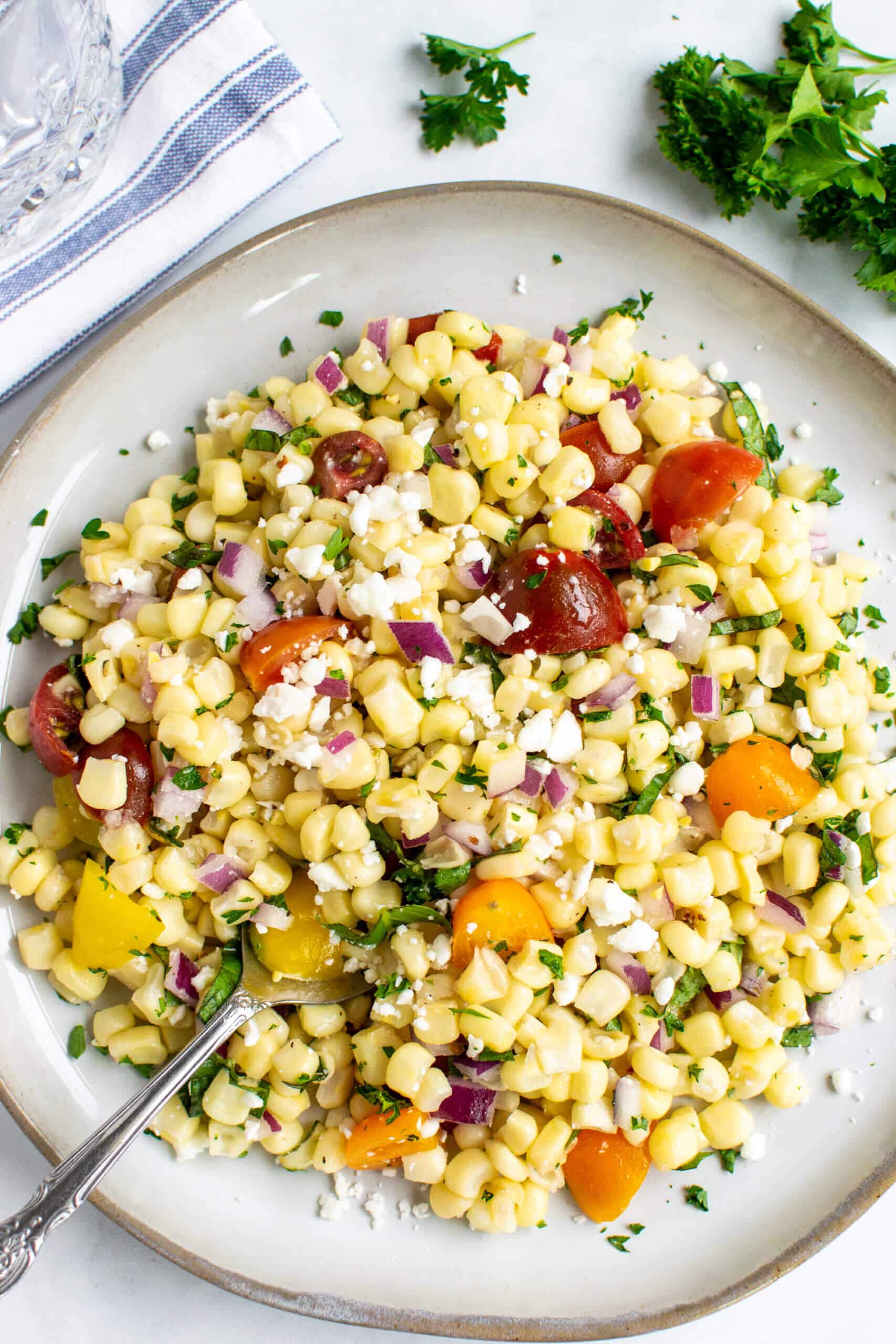 Sweet corn salad on a plate with feta and tomatoes. 