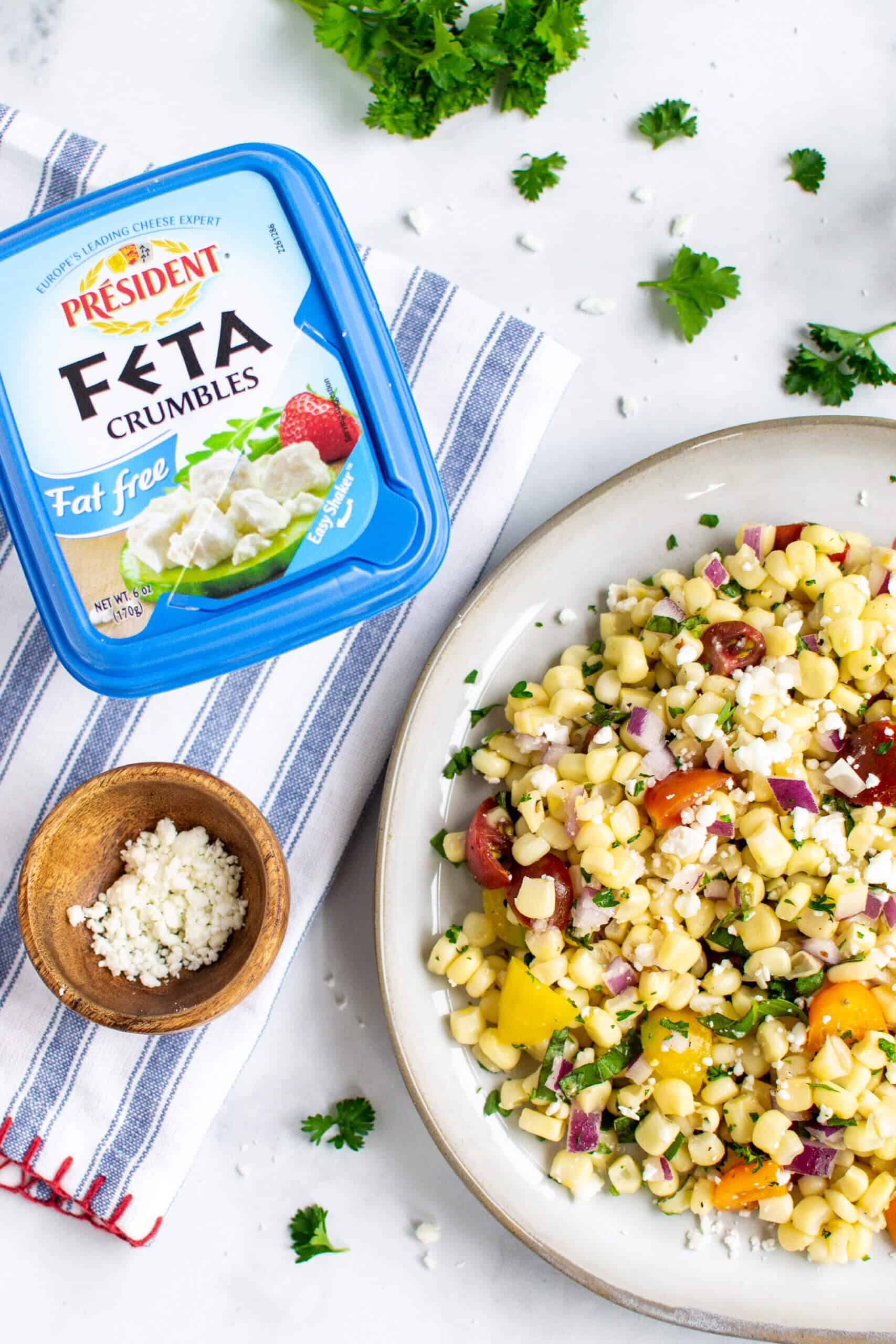Simple sweet corn salad on a plate with Président Feta Crumbles package.
