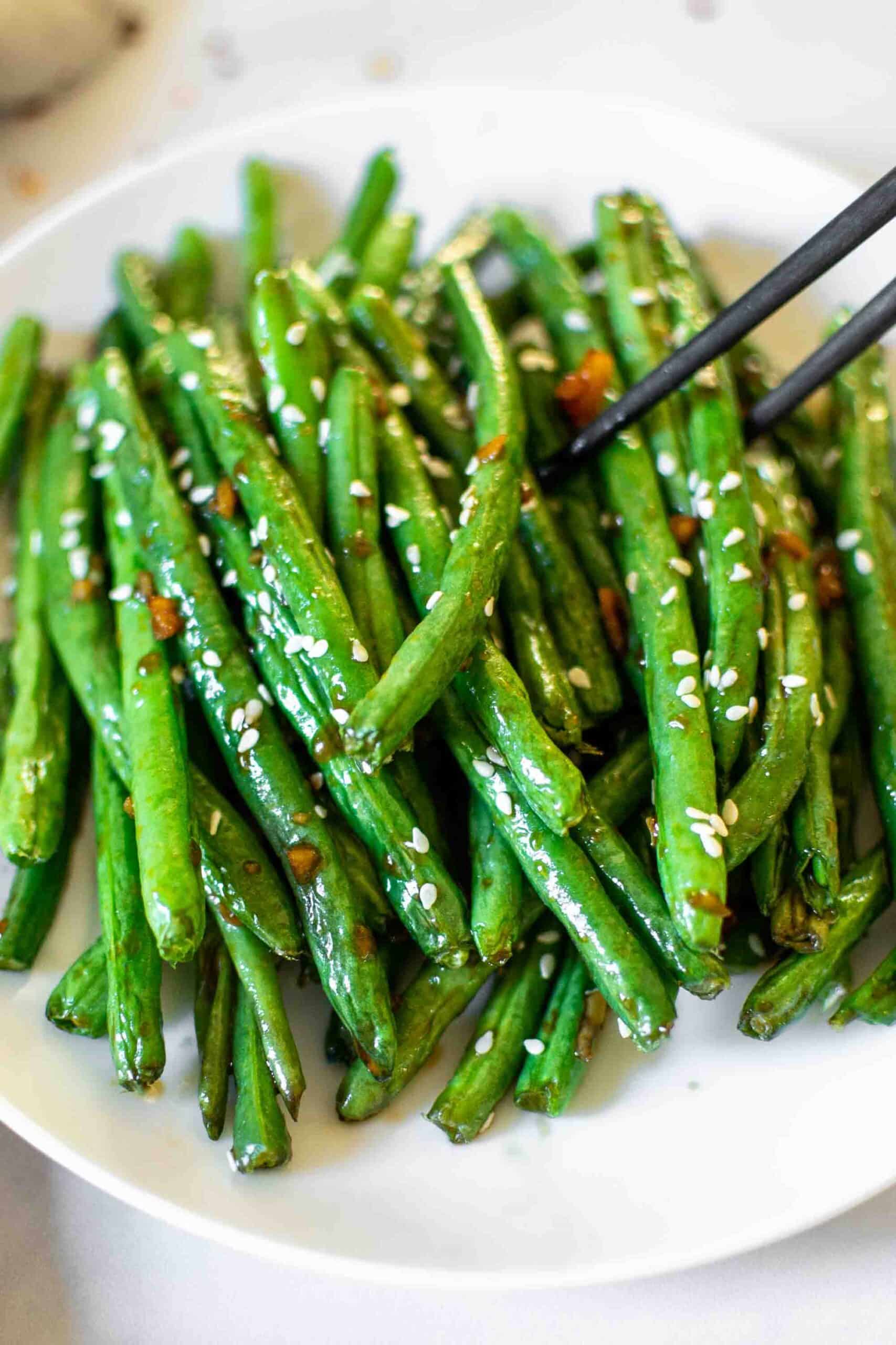 Chinese Style Air Fryer Green Beans on a plate with sesame seeds and chop sticks.