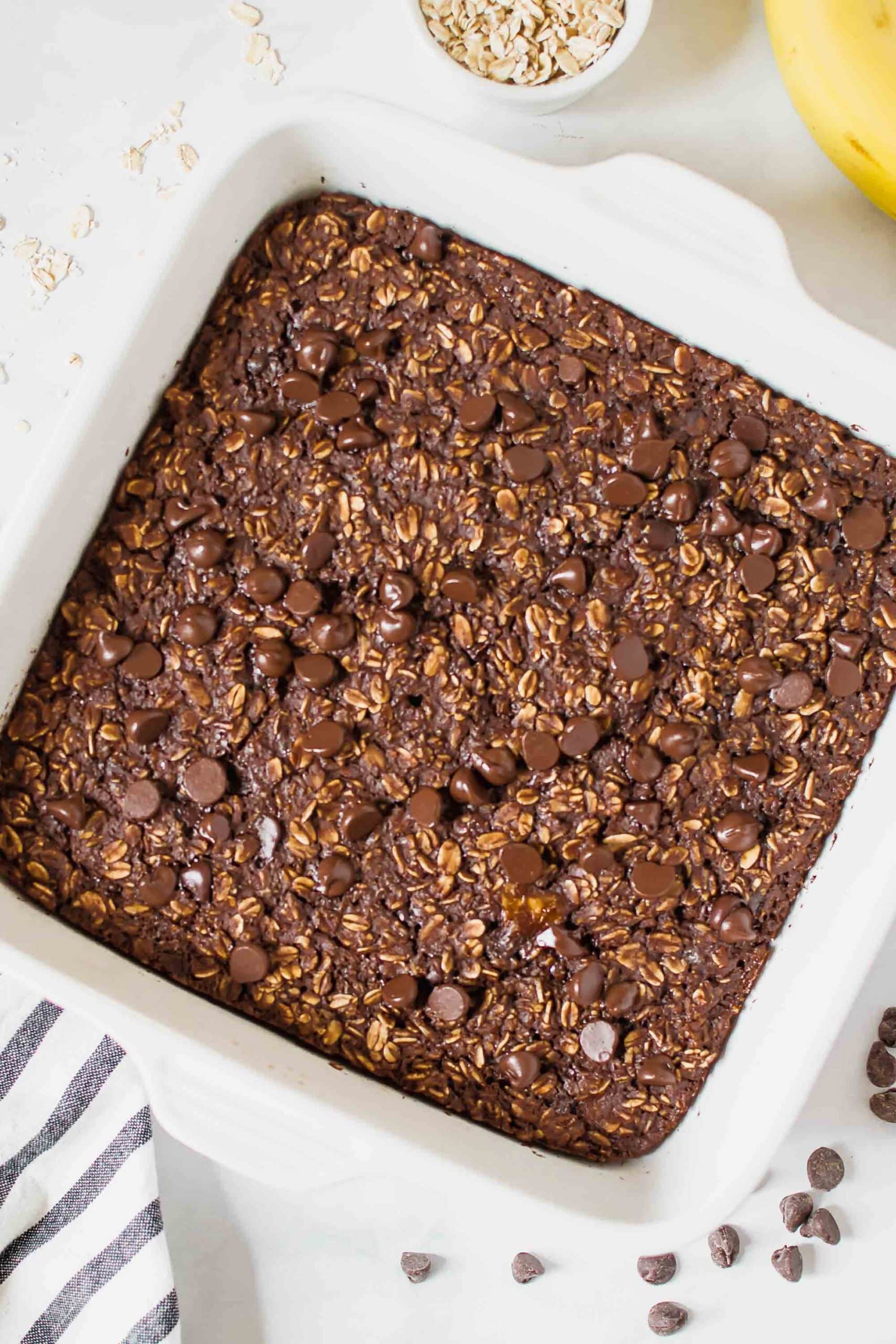 Chocolate Baked Oats in a white baking dish topped with chocolate chips