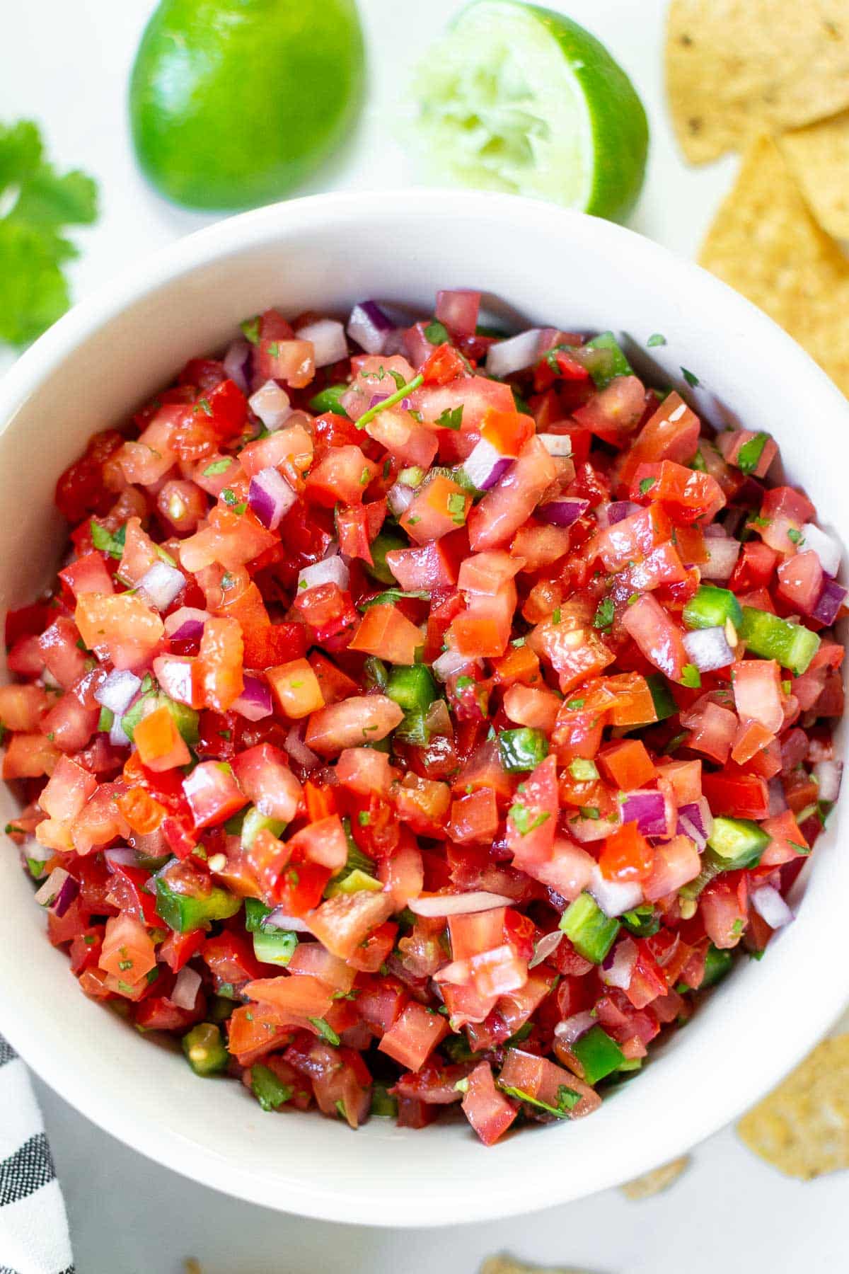 Pico de Gallo in a bowl with lime and chips.