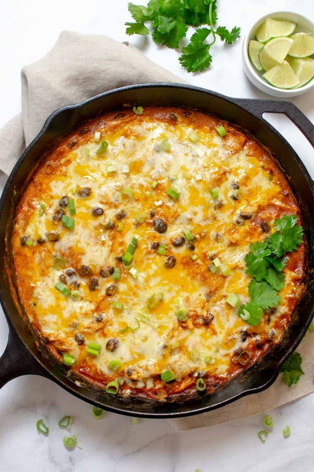 Creamy chicken enchilada skillet in an iron skillet topped with scallions