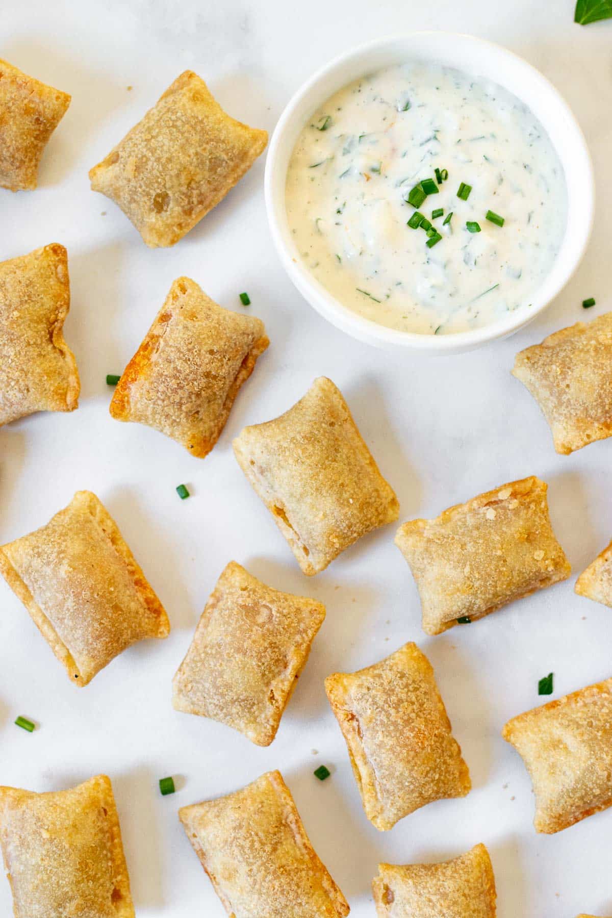a bunch of air fryer pizza rolls scattered on the table with ranch dressing.
