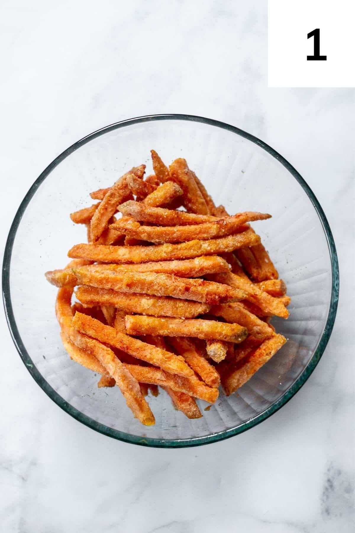 Frozen sweet potato fries in a bowl, seasoned.