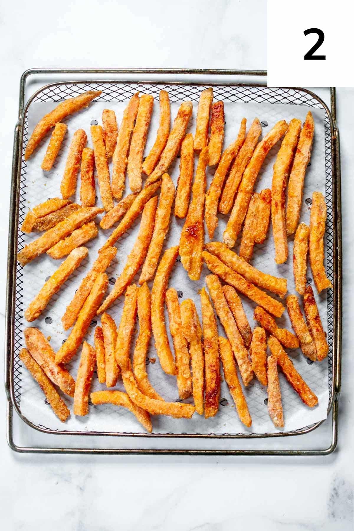 Frozen sweet potato fries on air fryer tray.