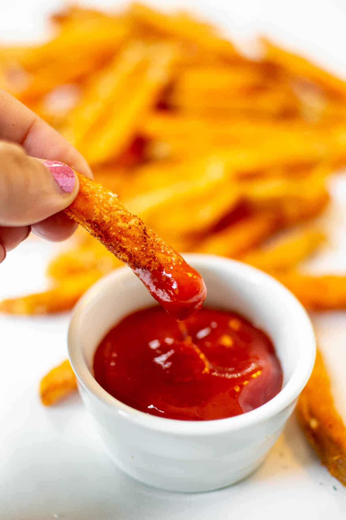 One sweet potato fry cooked in the air fryer dipped in ketchup.