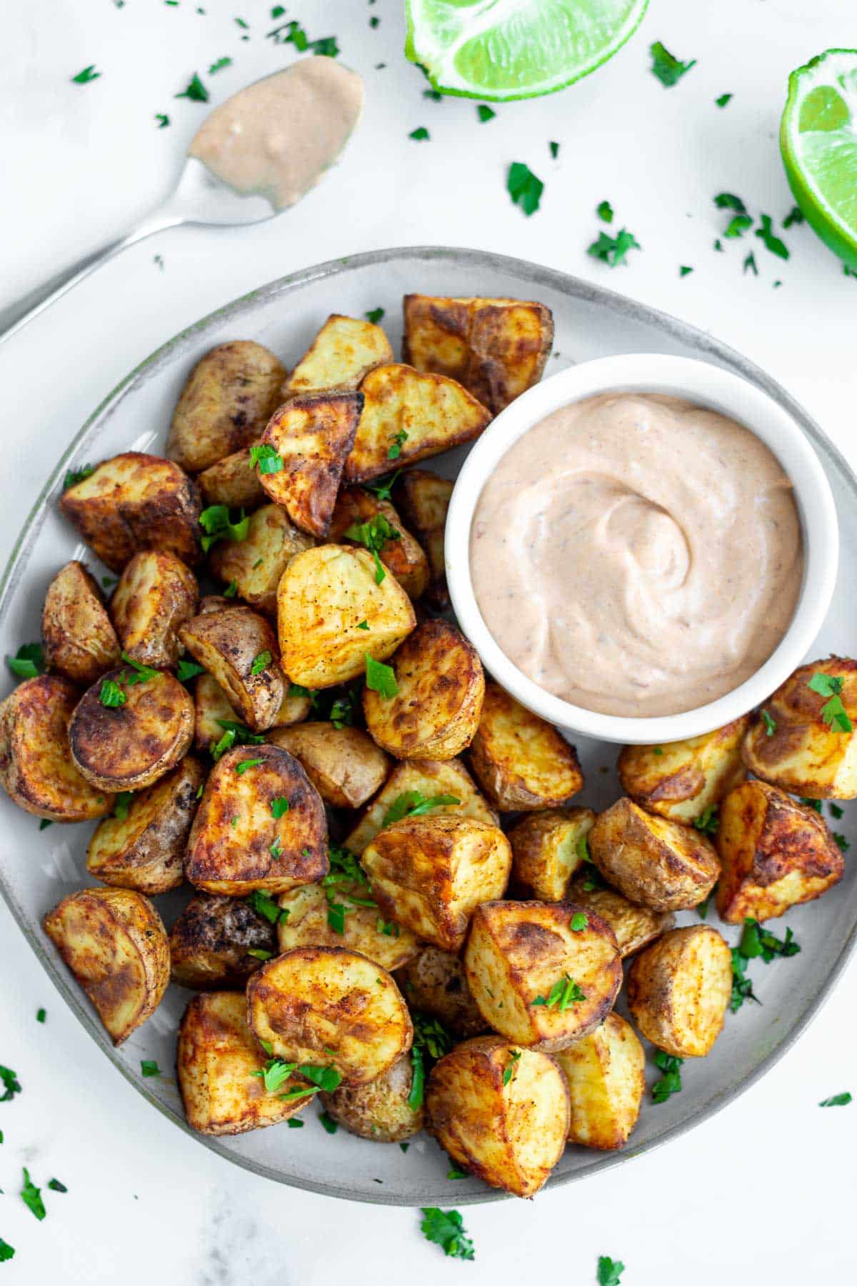 Air fryer roasted potato wedges with a small bowl of chipotle dipping sauce.