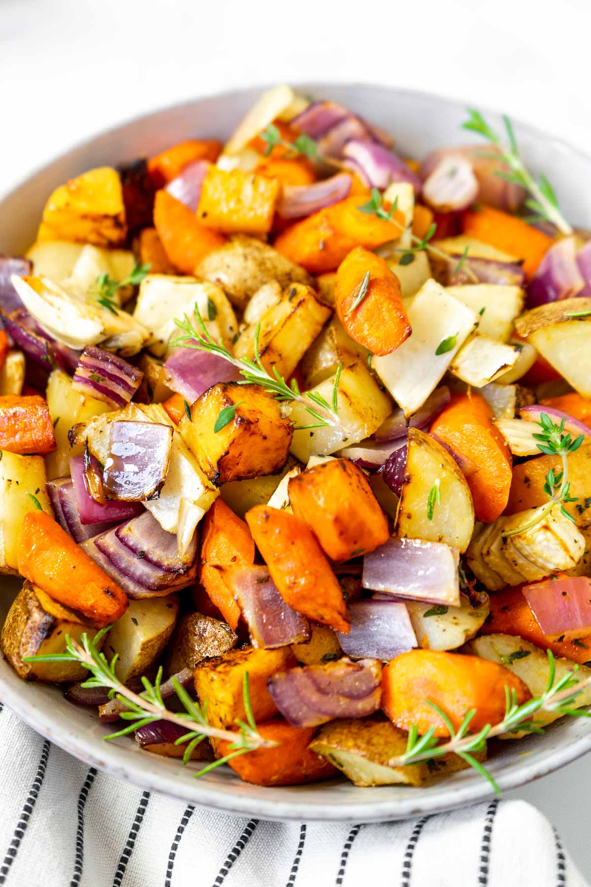 Air fryer roasted root vegetables  in a bowl sprinkled with rosemary and thyme.