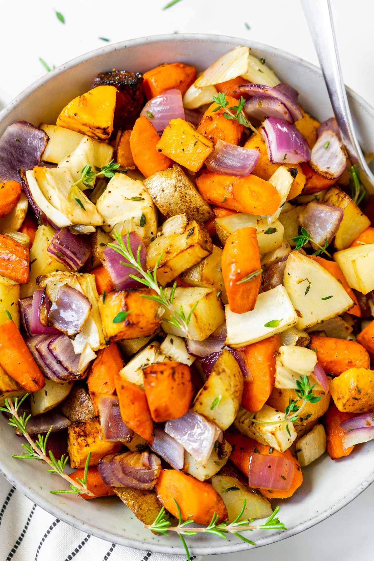 Air fryer roasted root vegetables in a bowl topped with herbs.