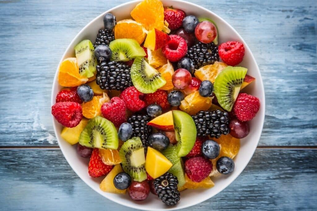 A fruit salad with berries and kiwi in a large white bowl