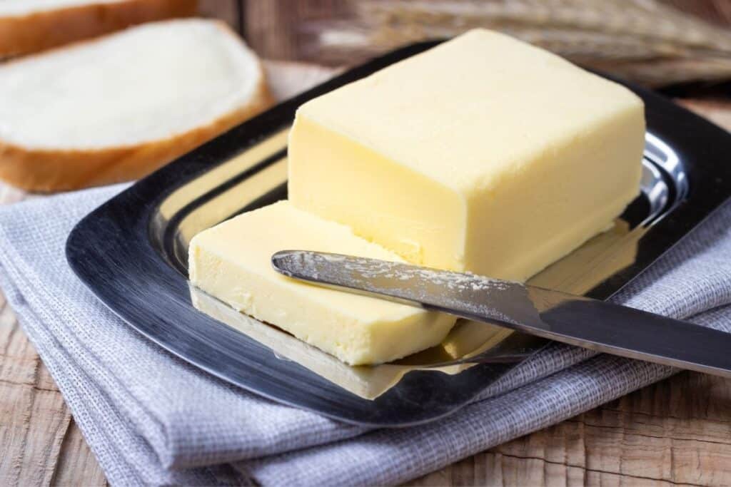 A stick of butter on a dish with a butter knife.