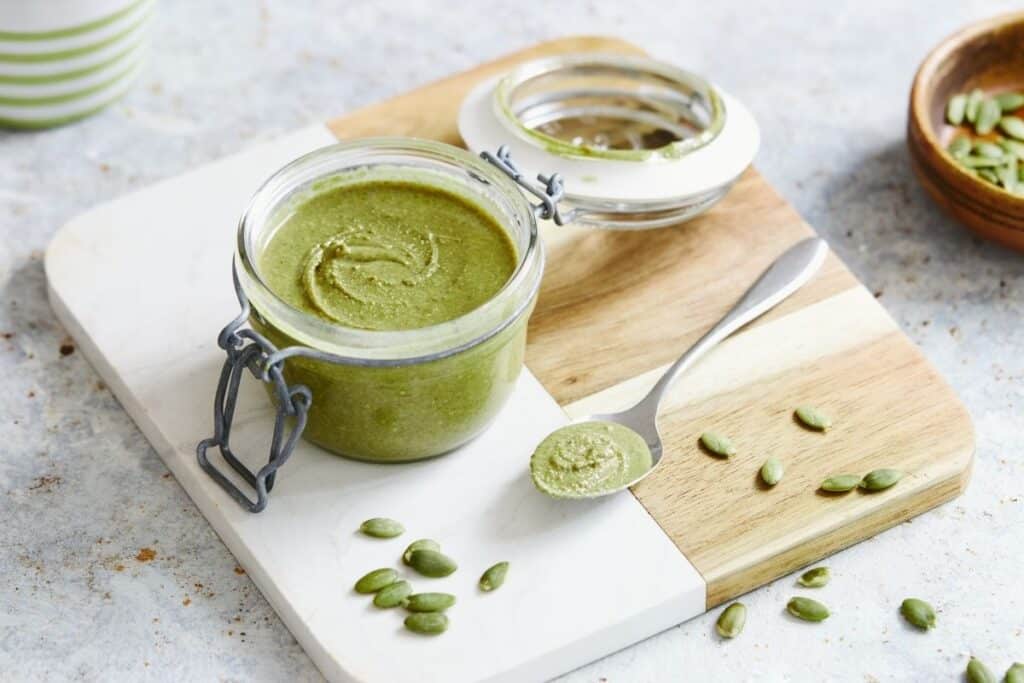 Green pumpkin seed butter in a small jar with a spoon