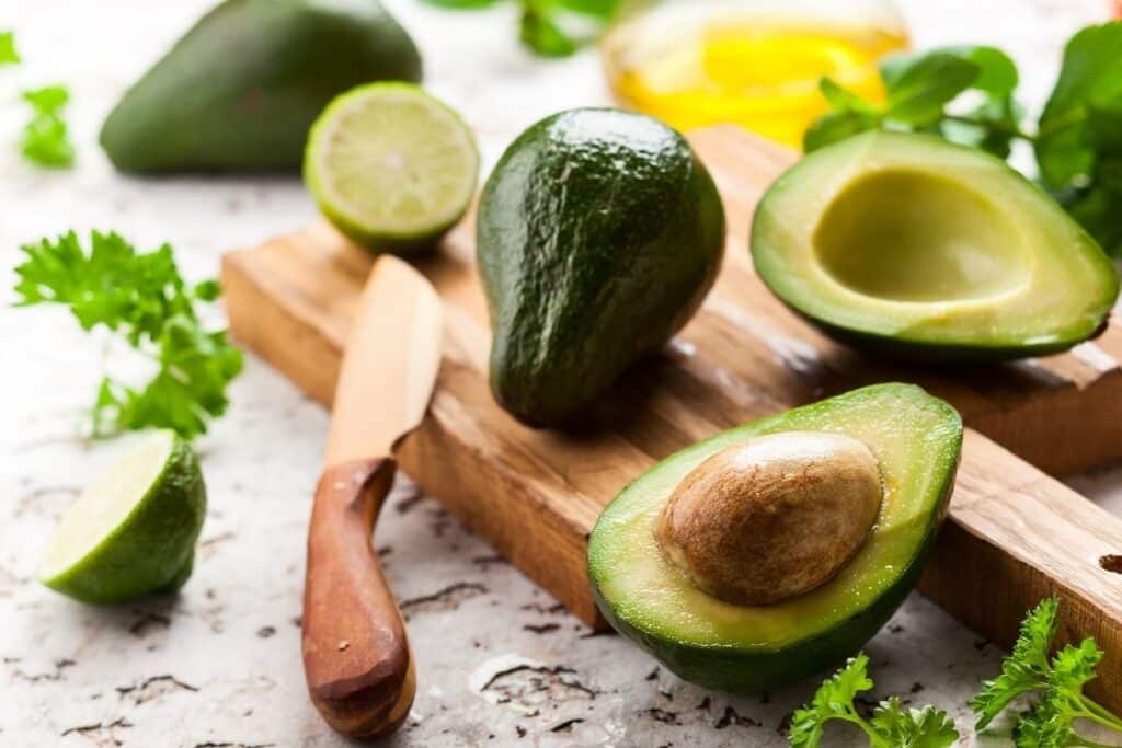 A cut avocado with a knife on a cutting board.