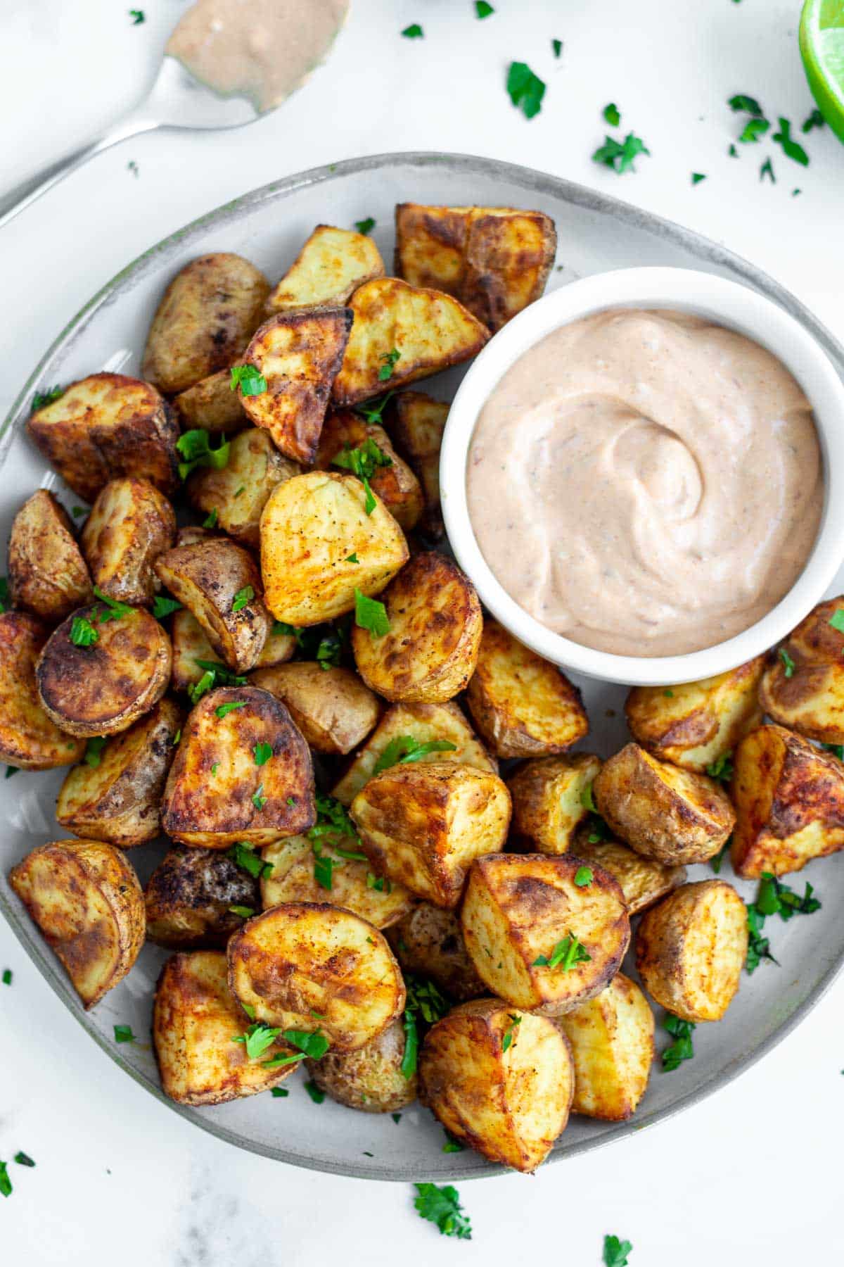 A plate of air fryer roasted potatoes with a small bowl of chipotle mayo.