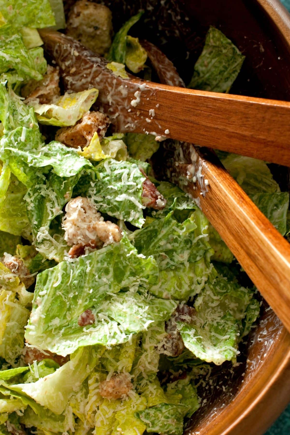 Close up of Caesar salad with serving spoons.