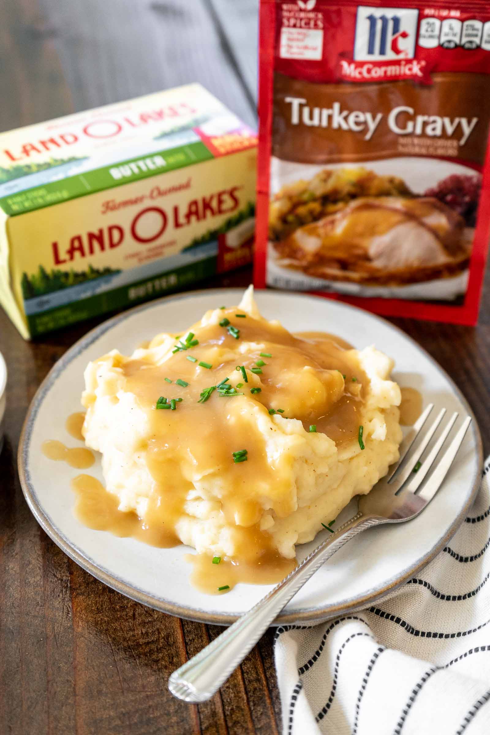 A plate of mashed potatoes and gravy with Land o Lakes Butter and McCormick Gravy packet