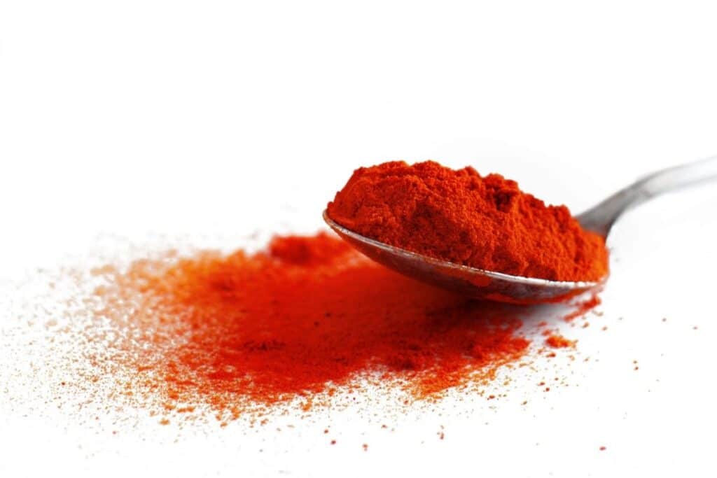 Sweet paprika on a spoon on a white background.