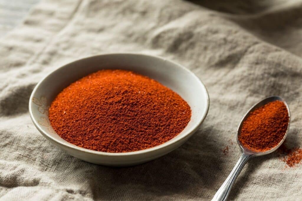 Smoked paprika in a white bowl with a spoon.