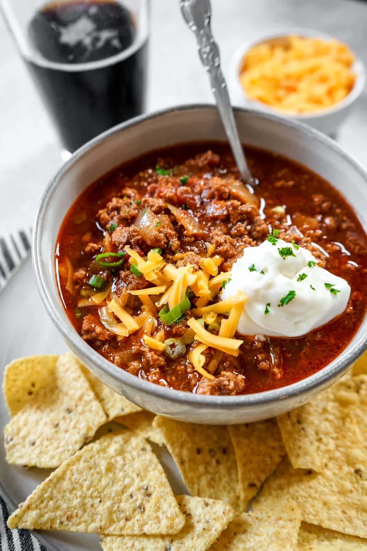 a bowl of chili con carne garnished with sour cream, cheese and onions.
