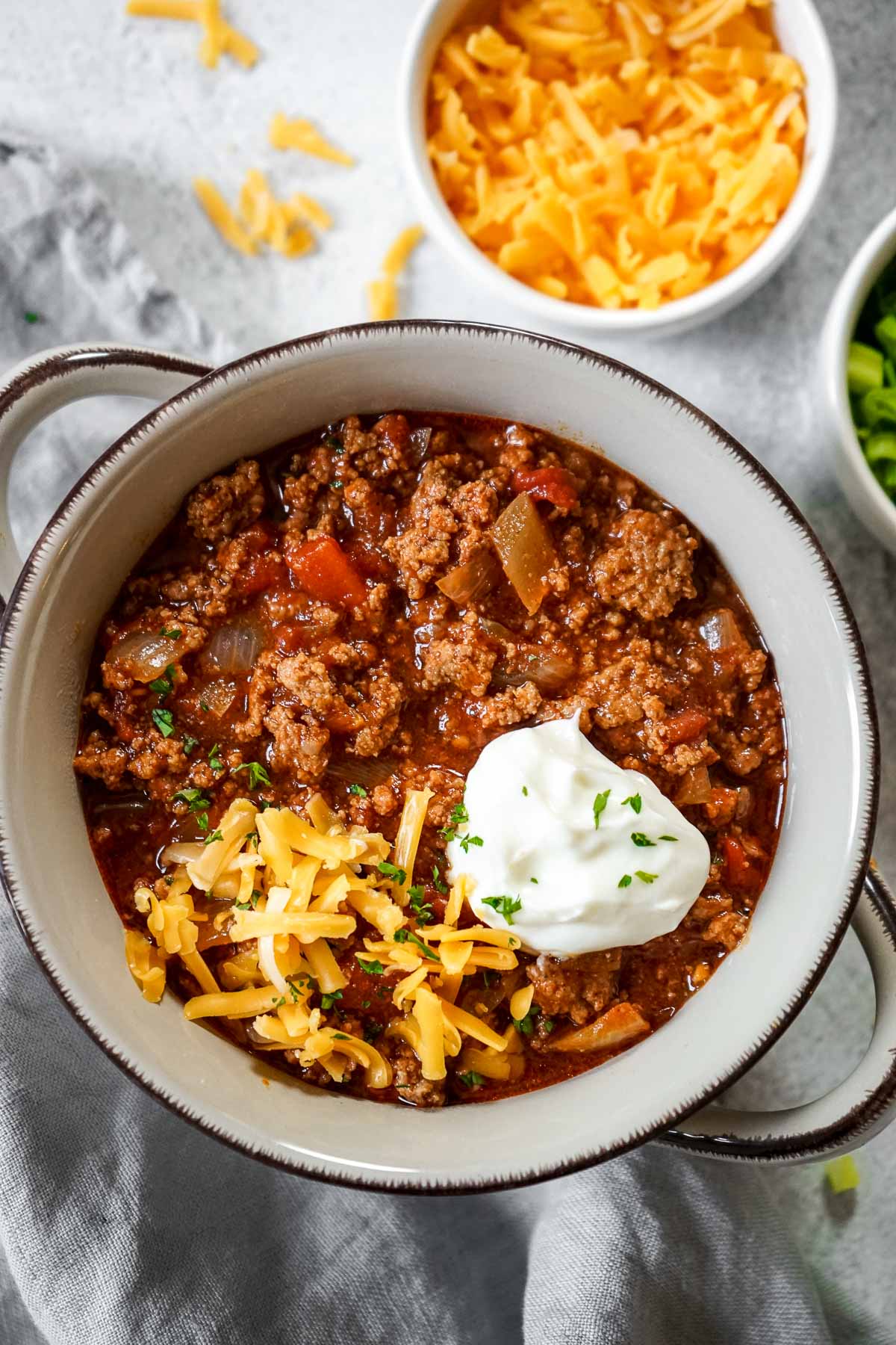 Easy chili con carne without beans in a bowl topped with sour cream and cheese.
