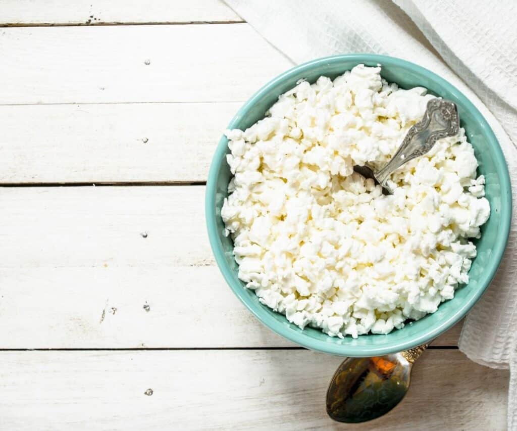 A bowl of cottage cheese on a table with a spoon.