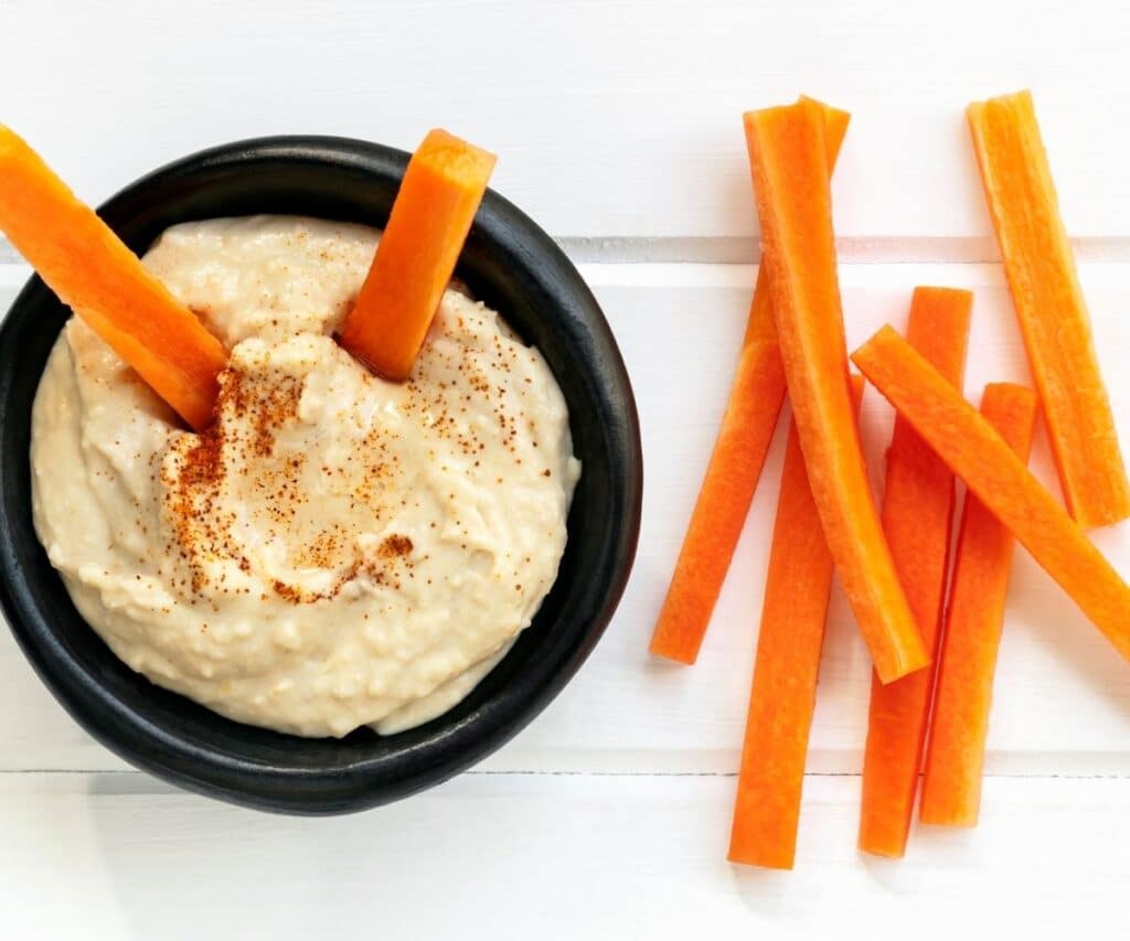 Carrots being dipped into hummus.