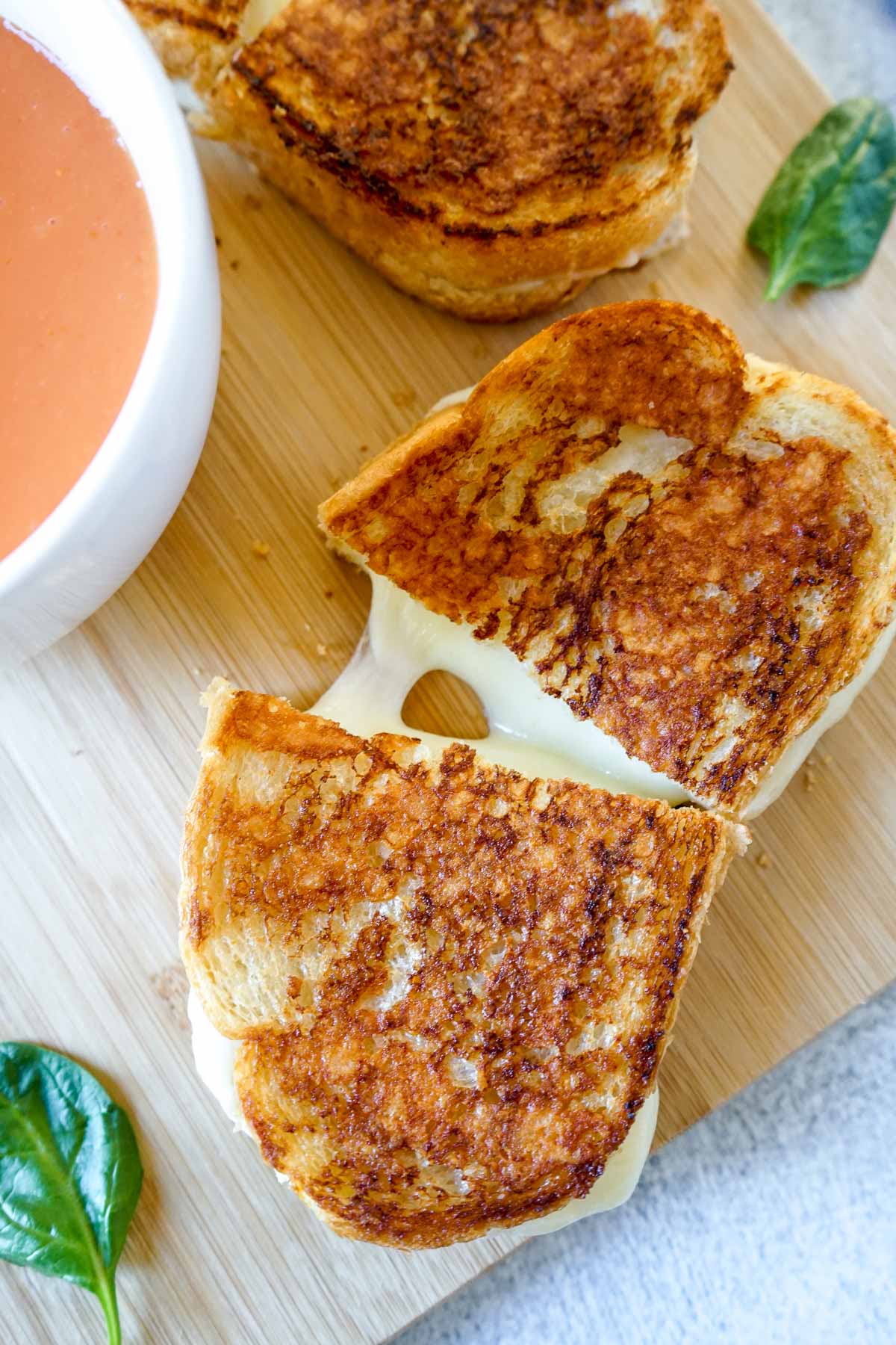 Copycat Starbucks grilled cheese on a cutting board with tomato soup with cheese oozing out.