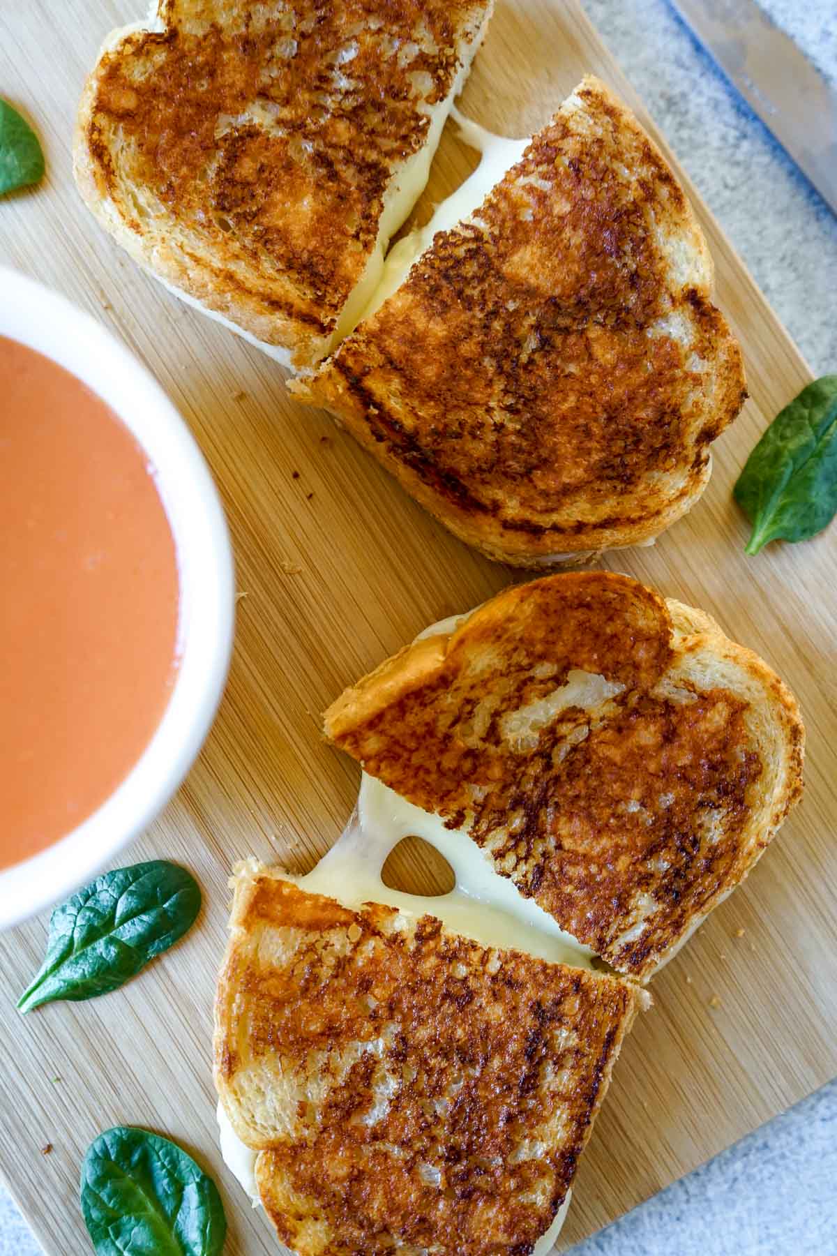 Two Copycat Starbucks grilled cheese on a cutting board with tomato soup.