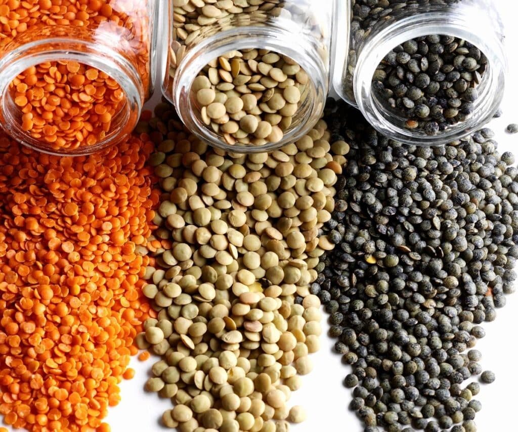 Three different colors of lentils spilled out on the counter.