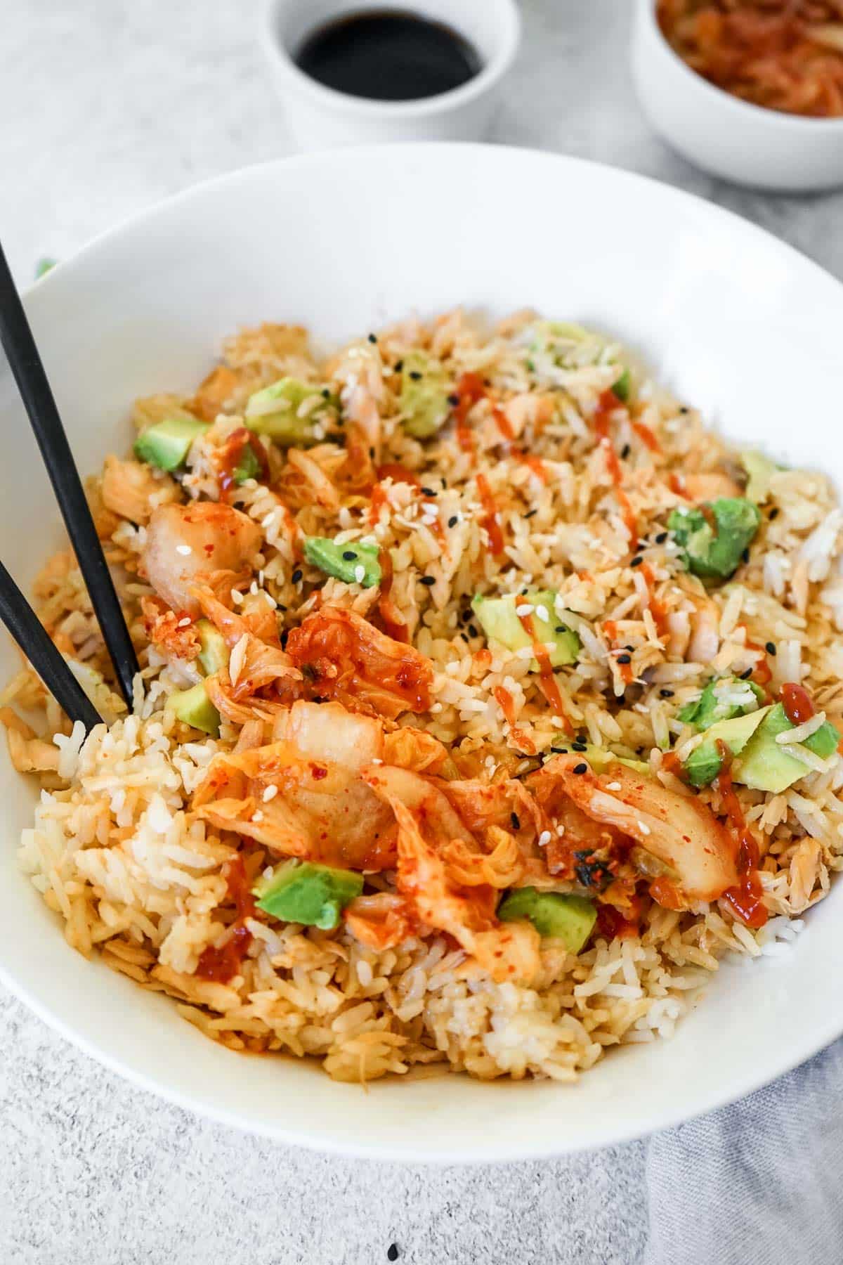 TikTok Rice Bowl with Salmon in a white bowl with kimchee and chop sticks.