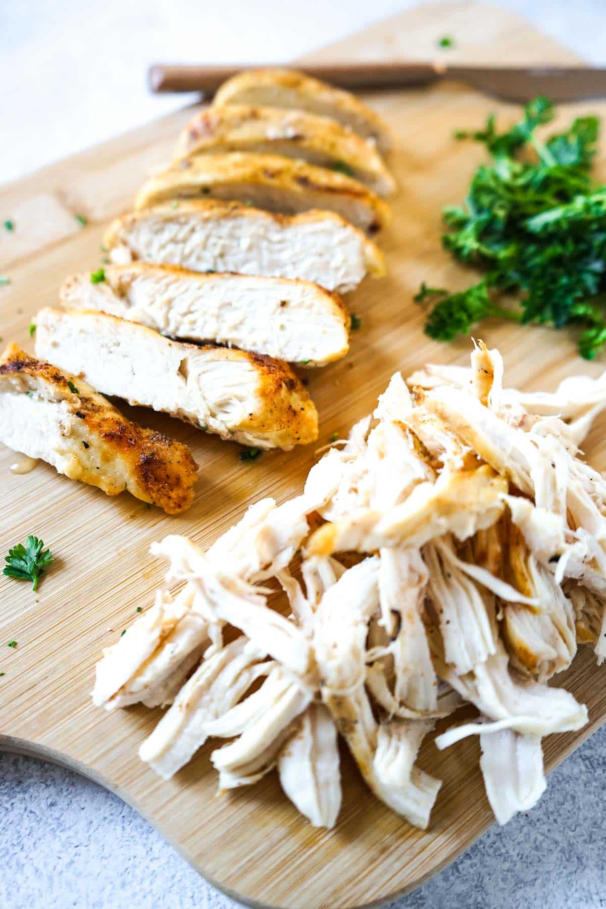 Sliced chicken breast and shredded chicken breast cooked in the air fryer on a cutting board.