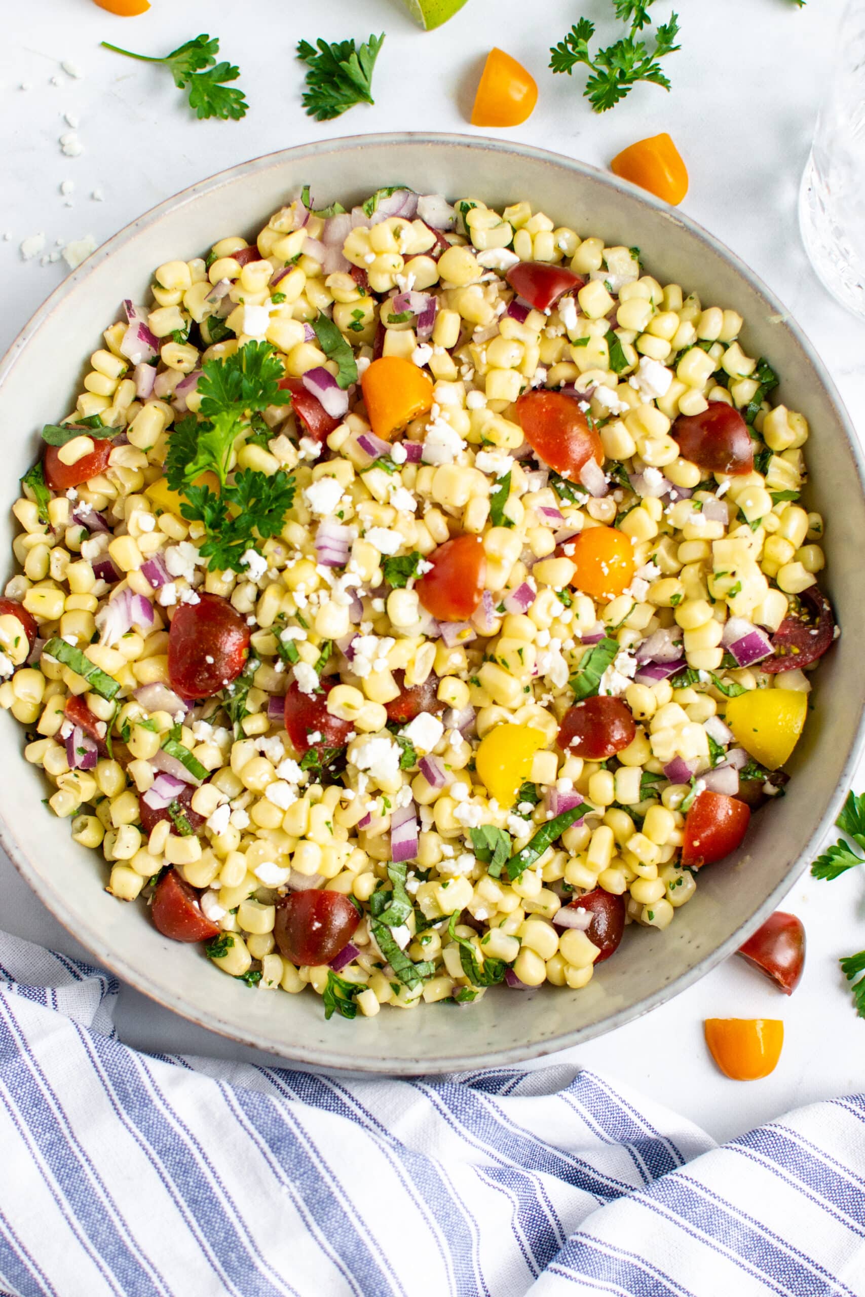 Corn salad with tomatoes in a bowl with feta cheese.
