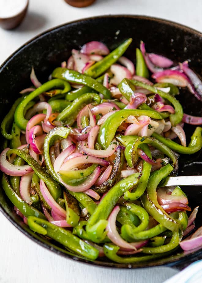 An iron skillet with peppers and onions.