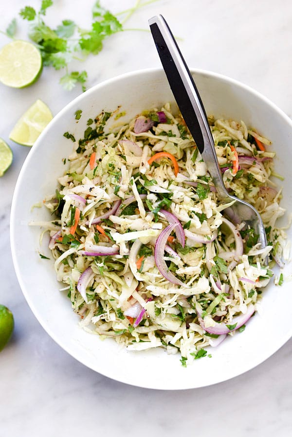 A white bowl with crisp Mexican cole slaw that is a great side for nachos.