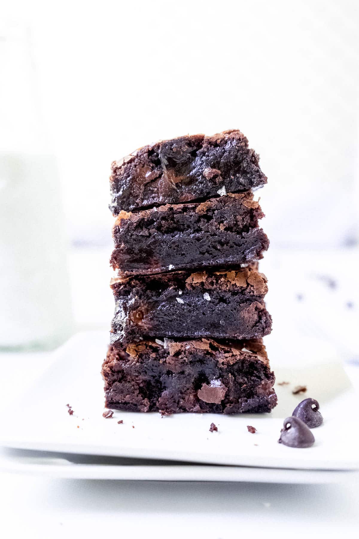 A stack of four fudgy boxed brownies on a white plate.