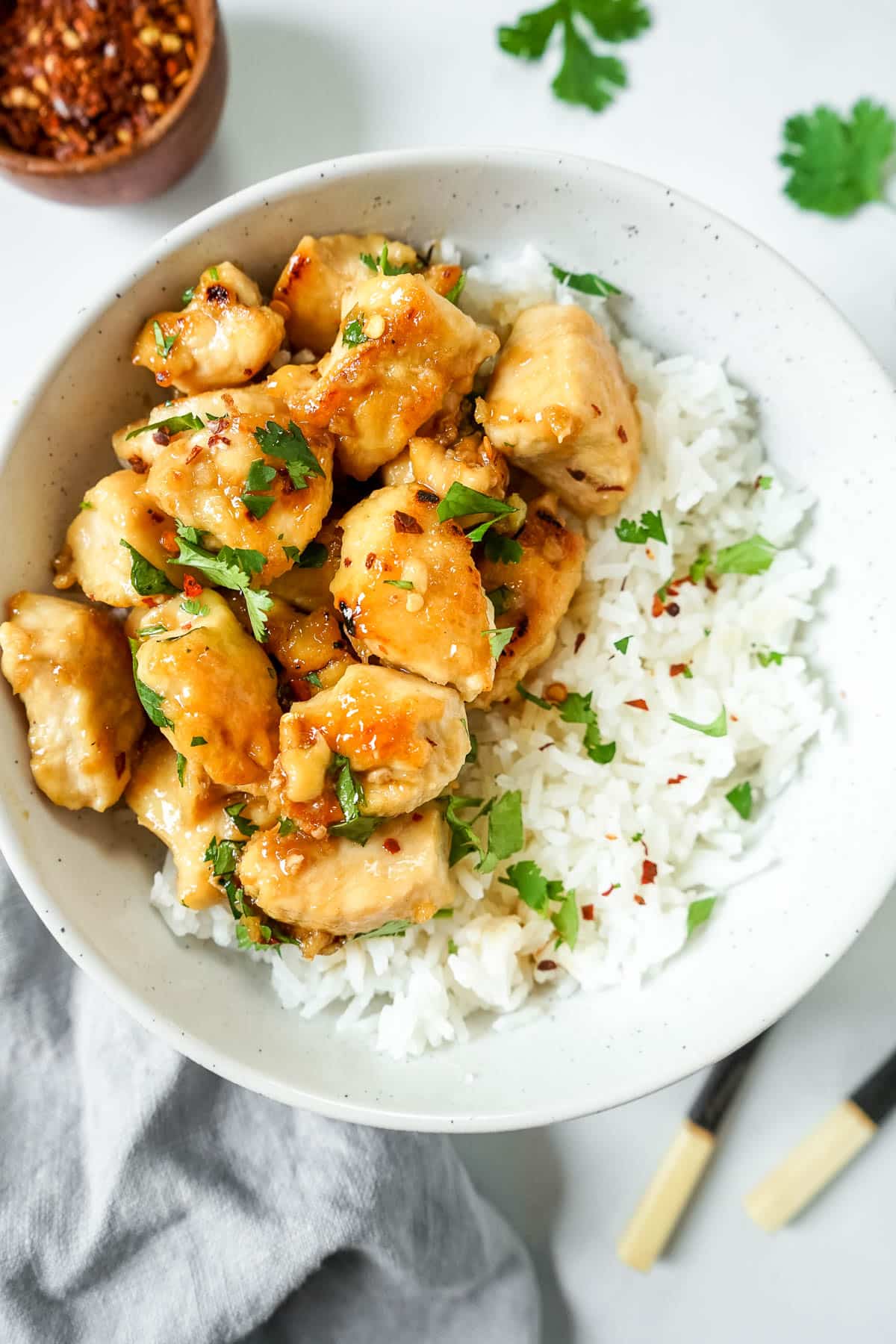 Honey butter garlic chicken in a bowl with rice, sprinkled with cilantrol.