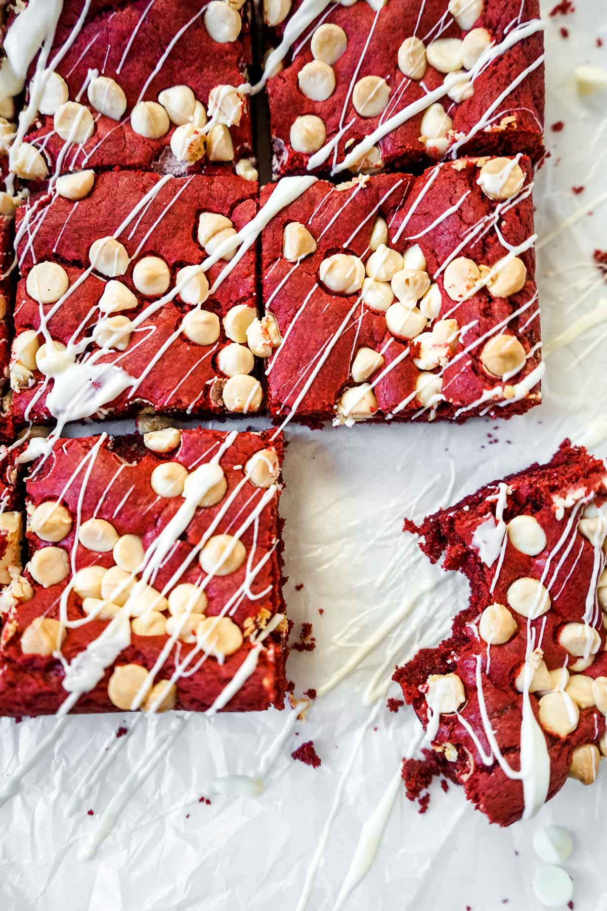 Red velvet brownies on a table with one piece with a bite taken out of it.