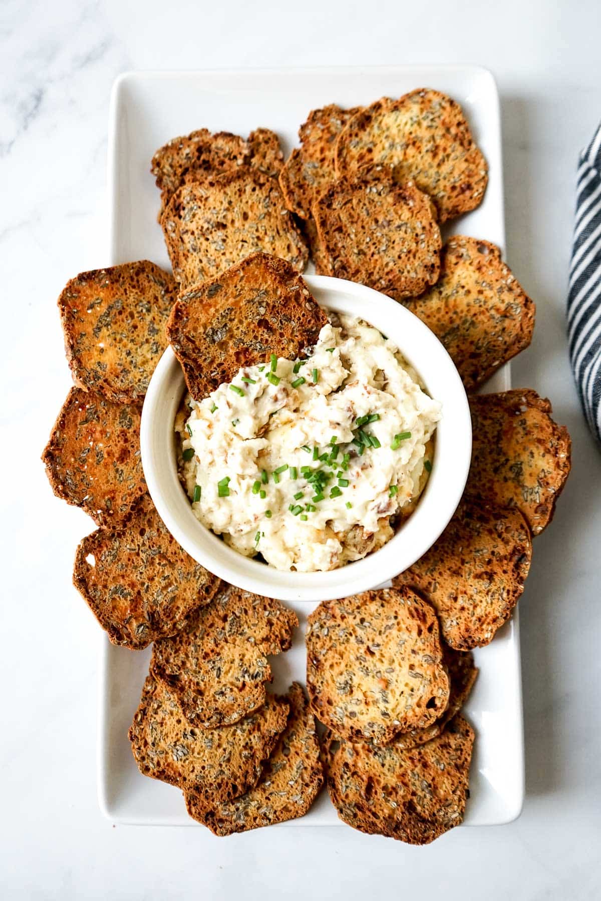 Swiss and bacon dip in a dish with a platter of crackers. 