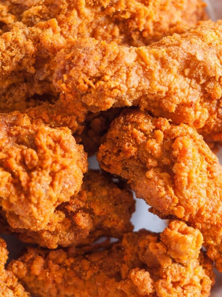 A unique topping for nachos is fried chicken. A plate of fried chicken legs.