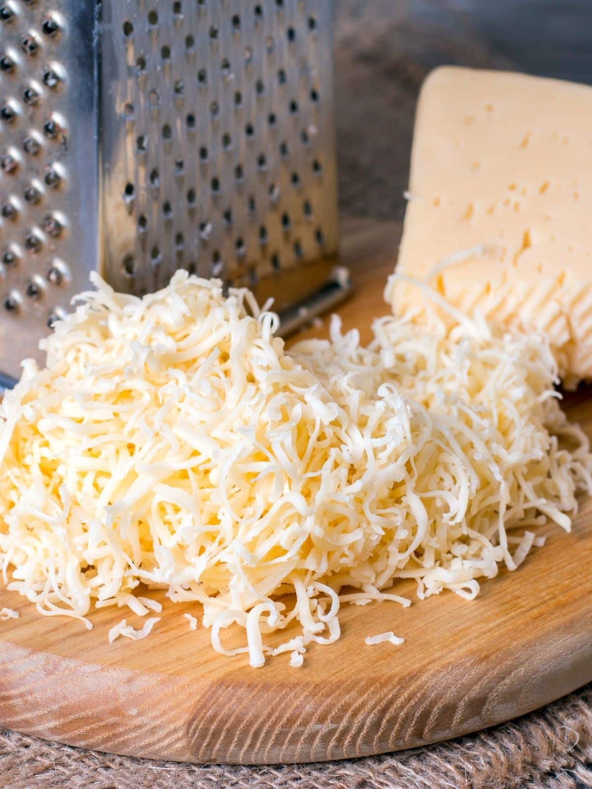 A wooden platter with shredded white cheese.